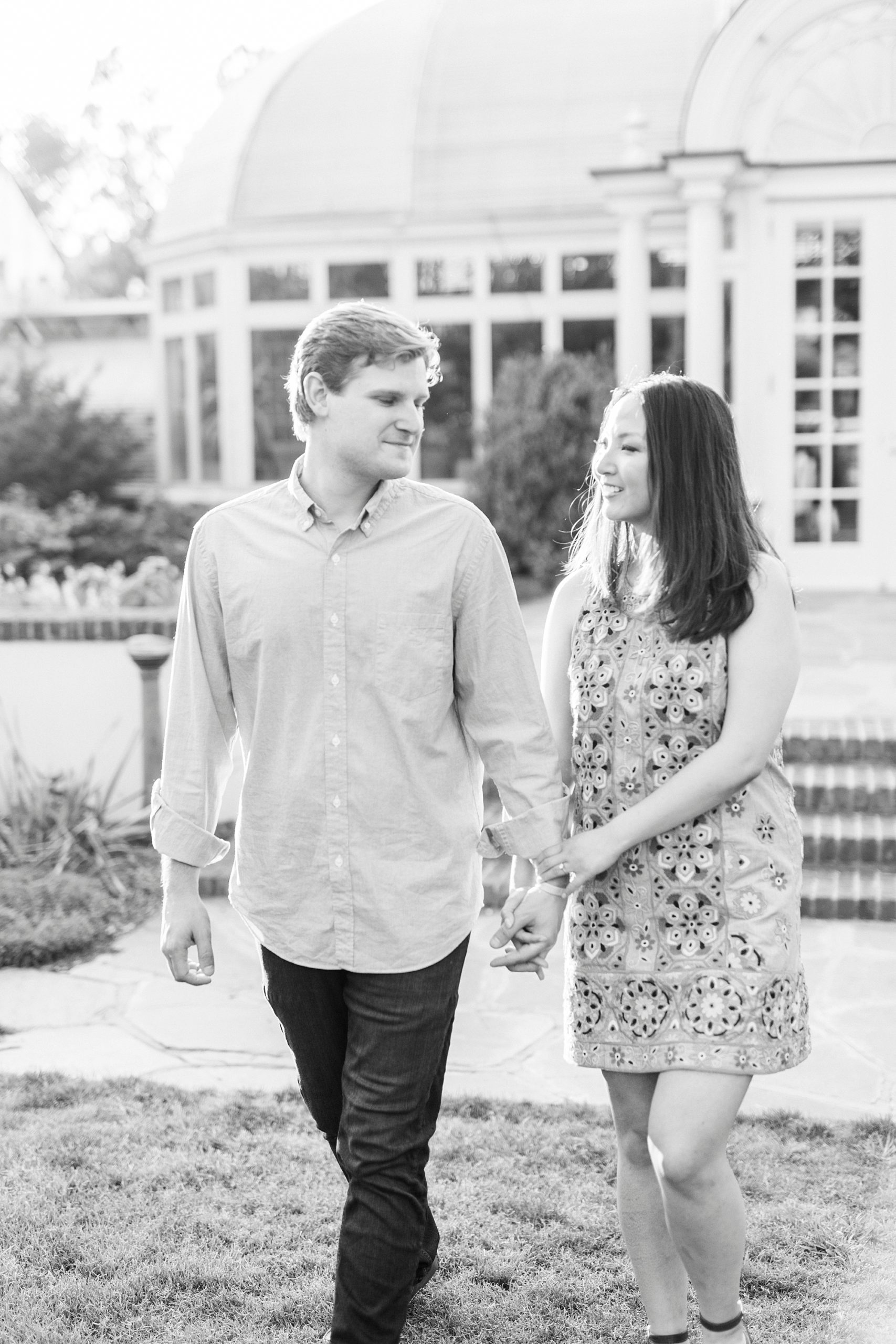 engaged couple holds hands walking on lawn at Reynolda Gardens