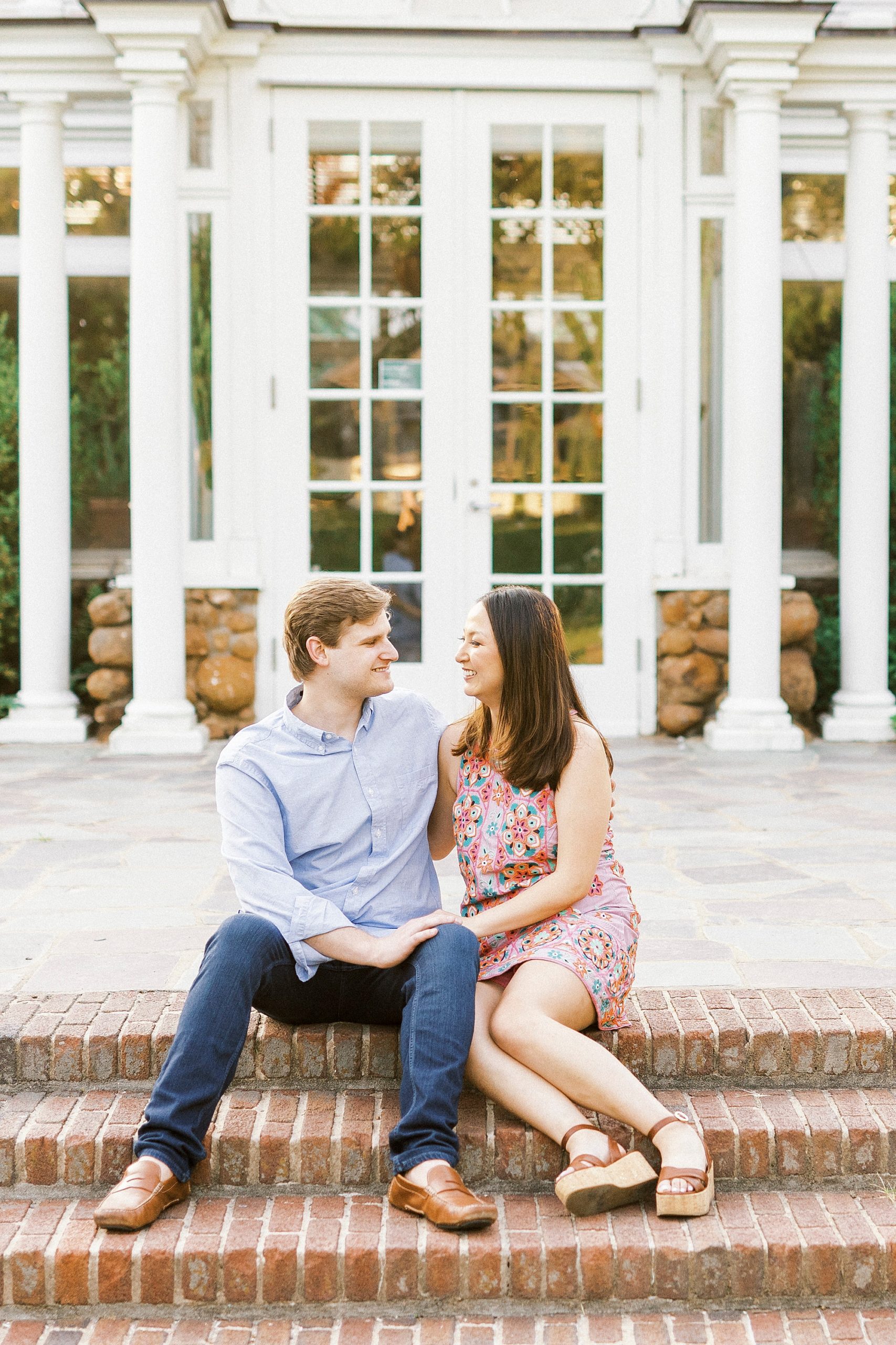 engaged couple sits together on brick steps at Reynolda Gardens