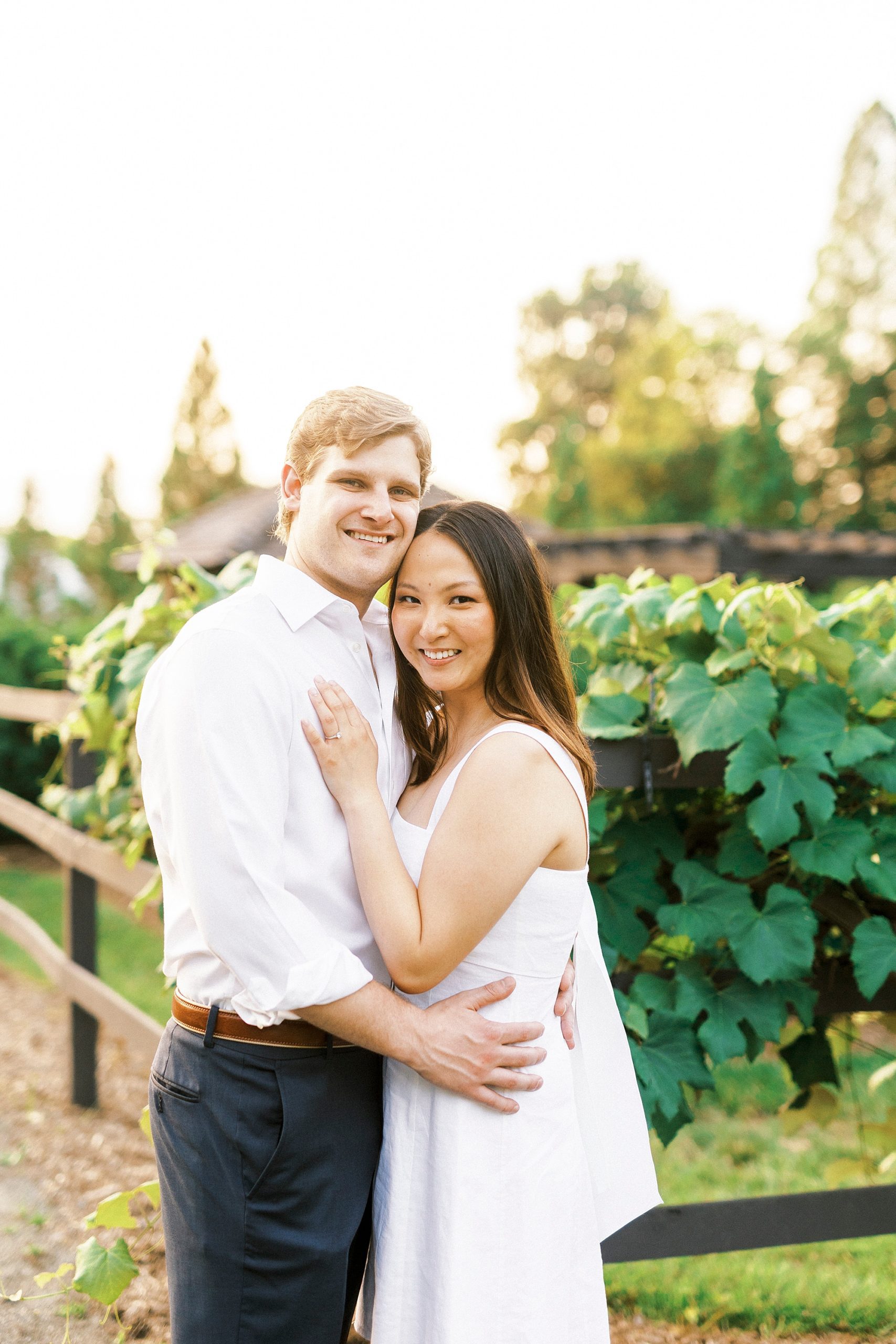 engaged couple hugs by vines at Reynolda Gardens