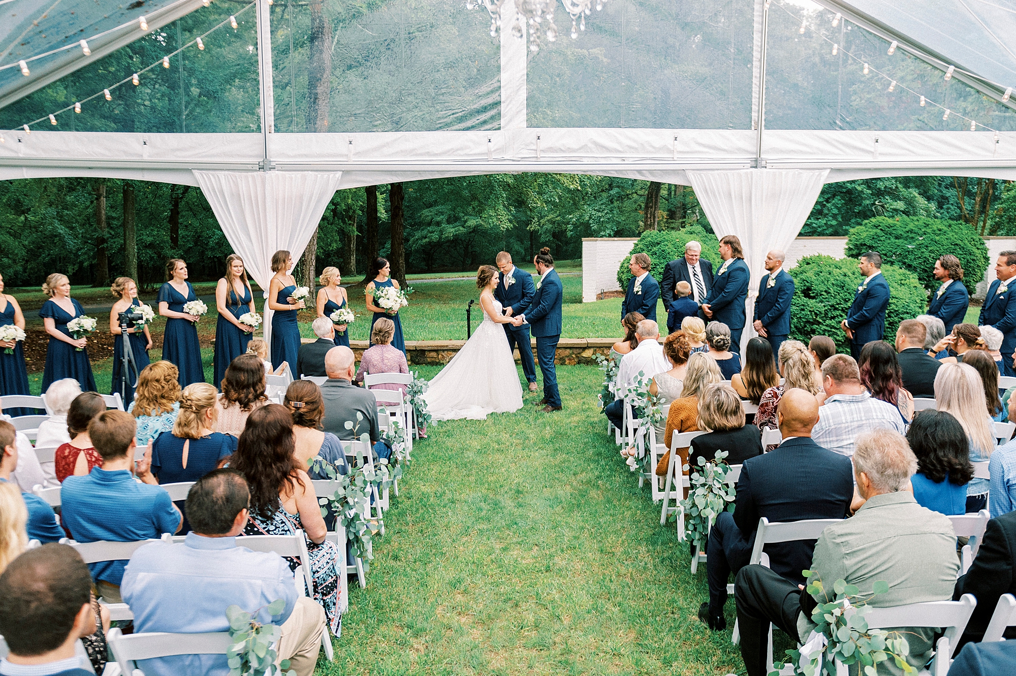 couple holds hands during ceremony on lawn of Boxwood Estate