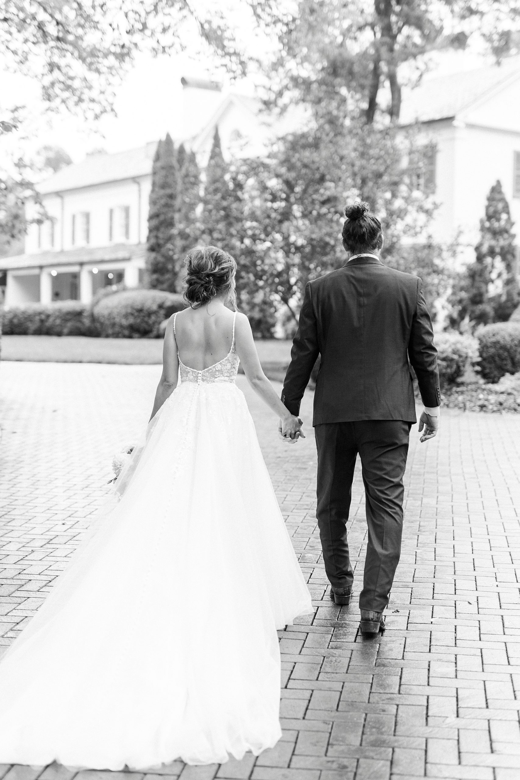 bride and groom hold hands walking on pathway at Boxwood Estate