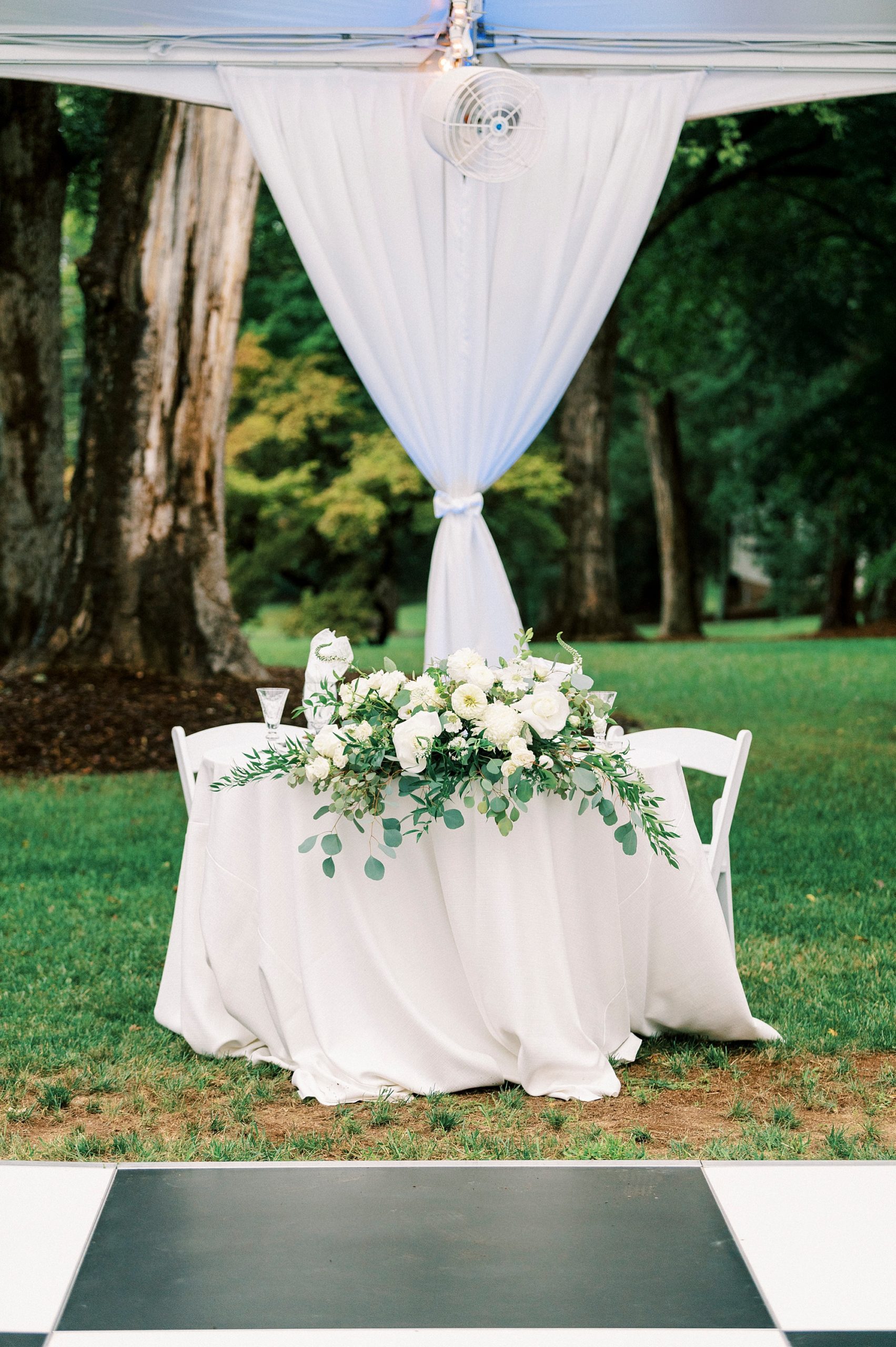 sweetheart table with ivory flowers by dance floor