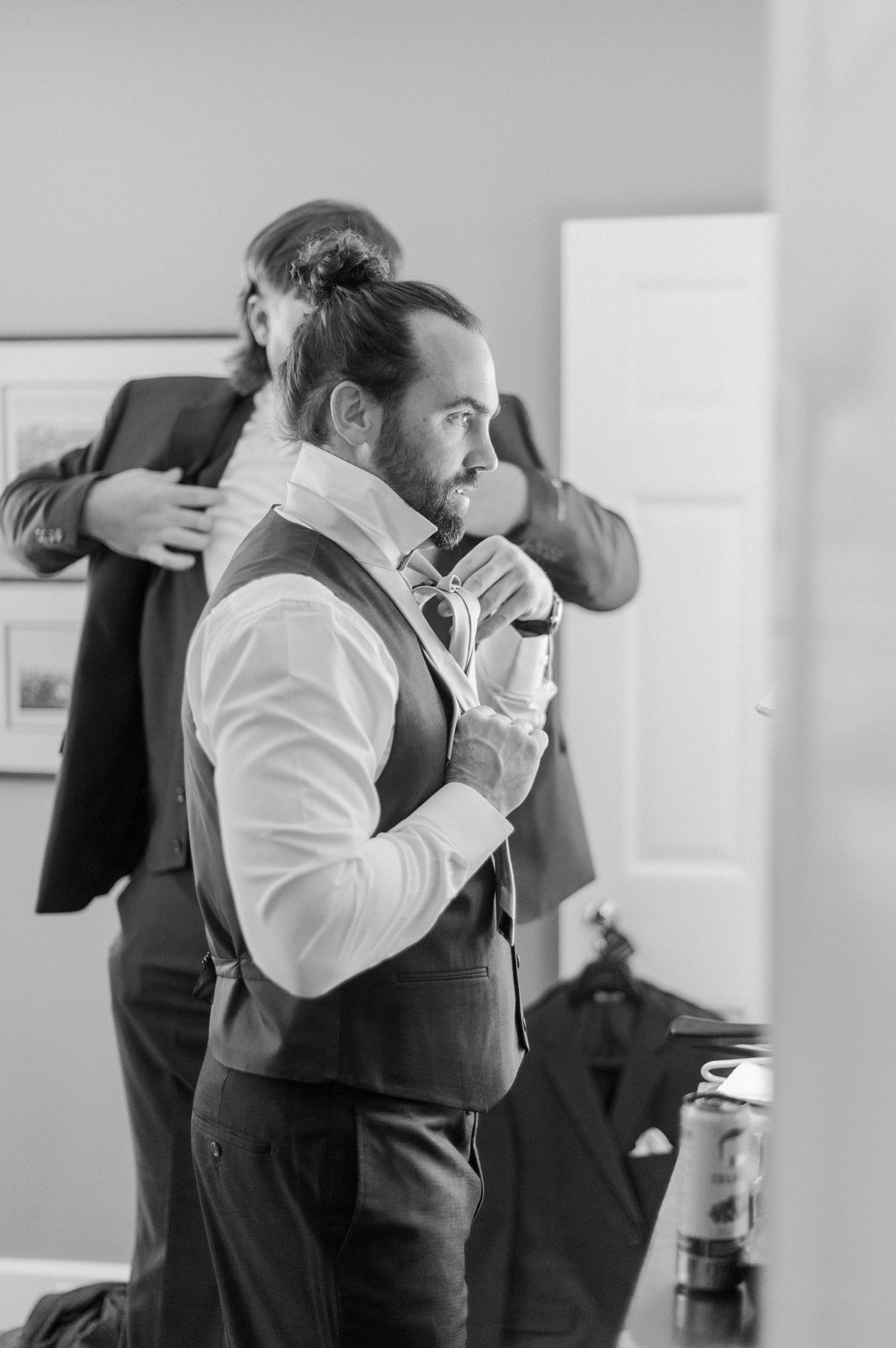 groom adjusts tie while preparing for NC wedding day