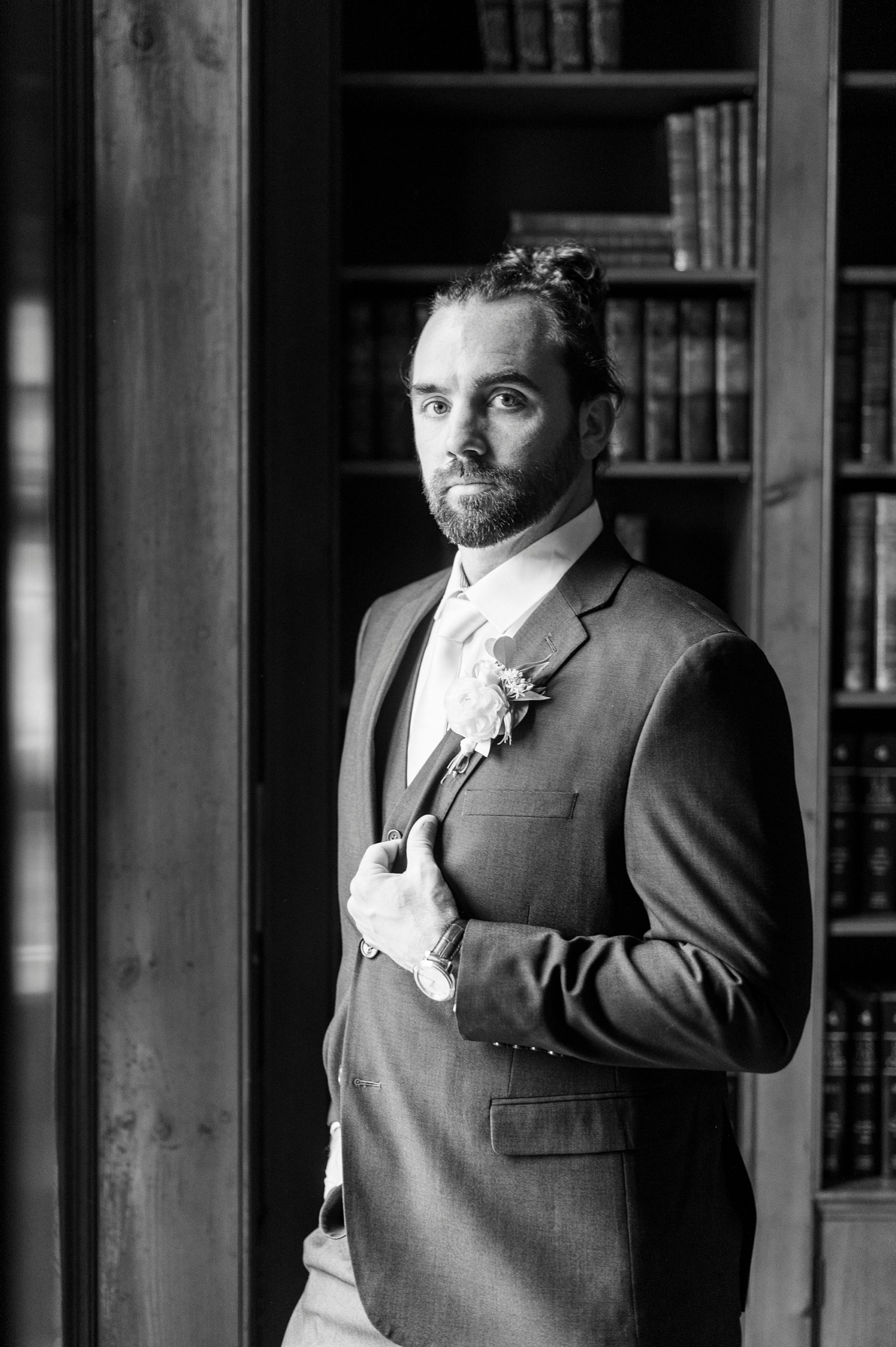 black and white portrait of groom by window in library at Boxwood Estate