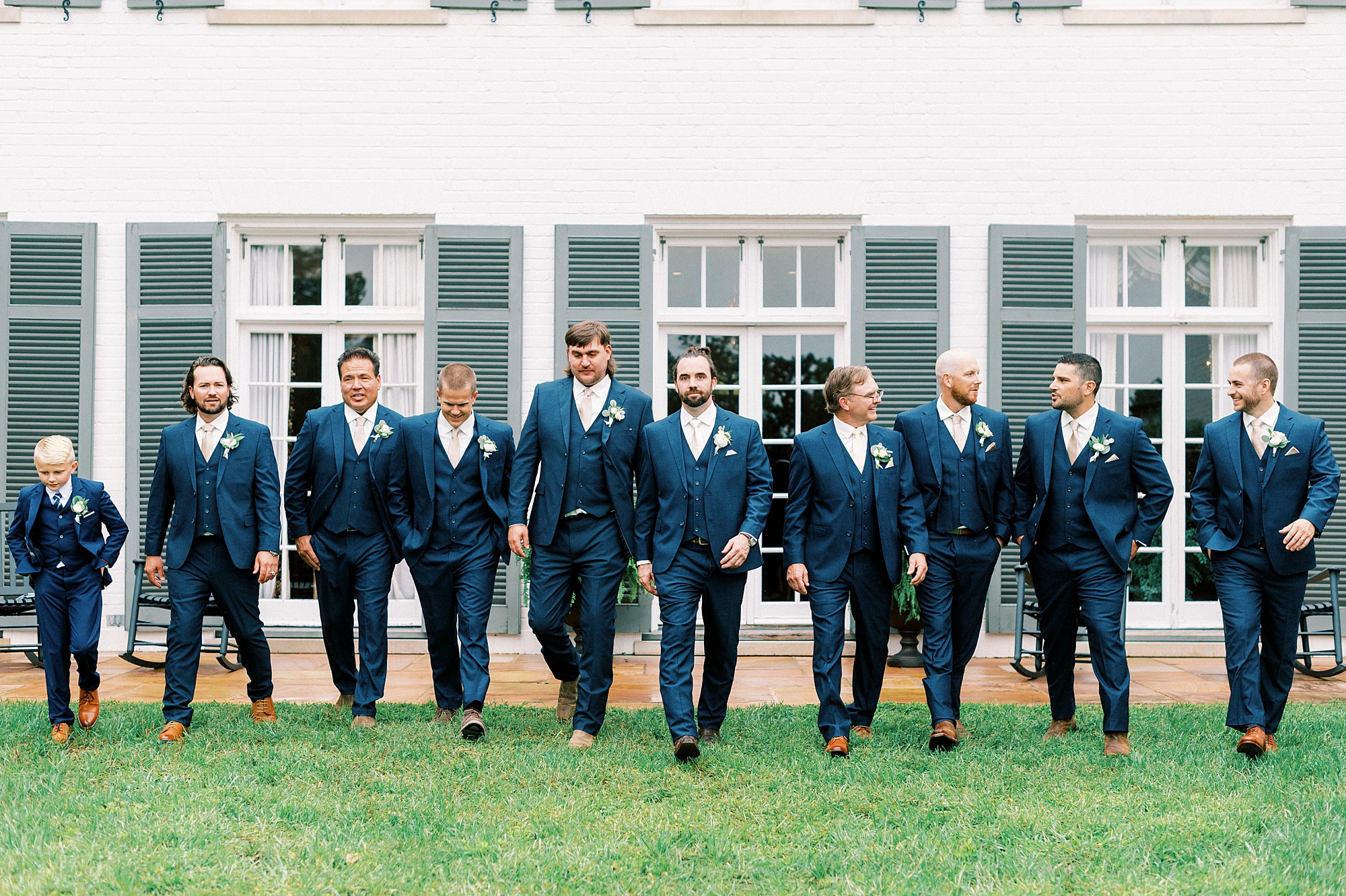 groom walks with groomsmen outside Boxwood Estate