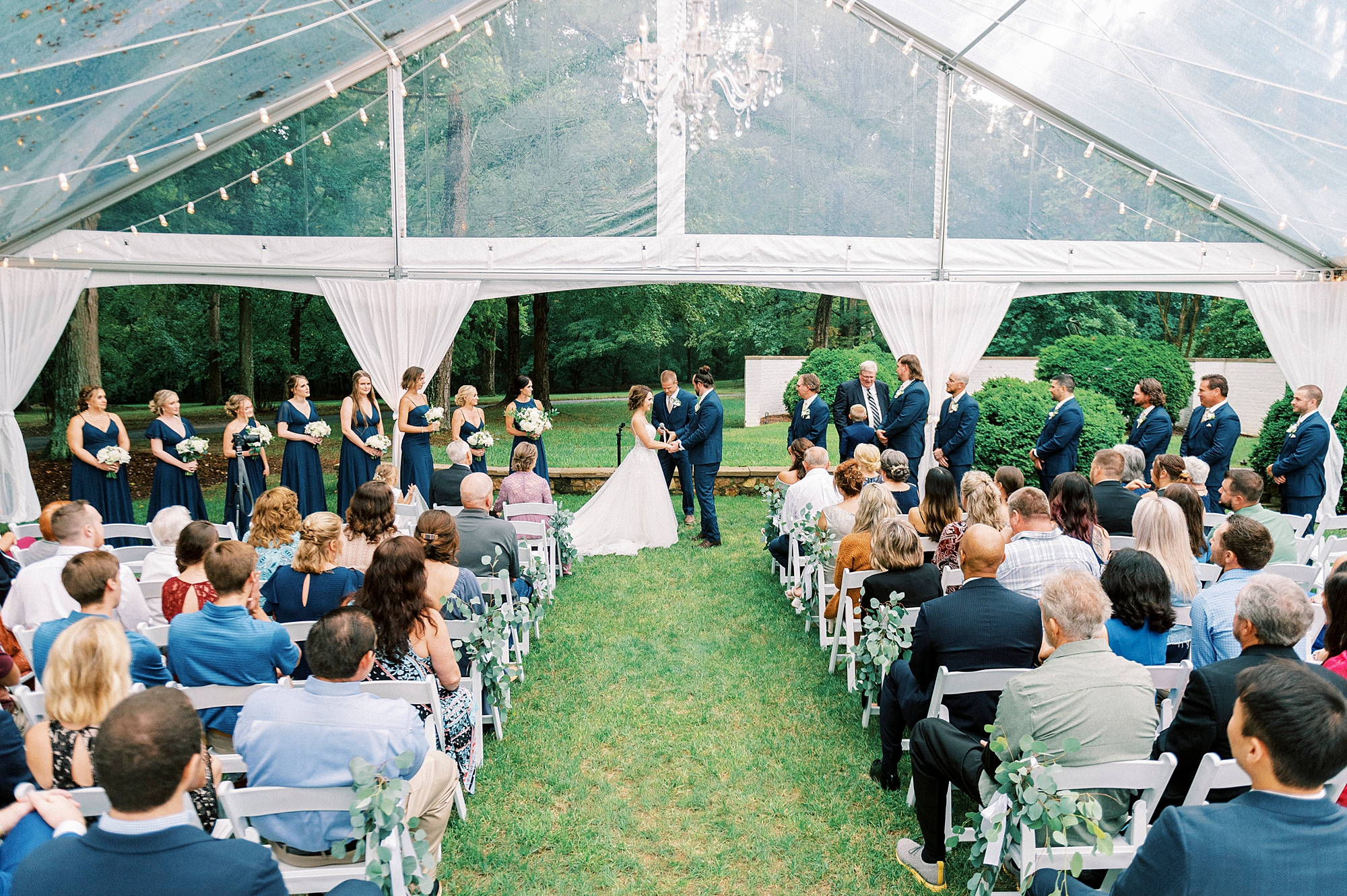 bride and groom hold hands during ceremony under tent at Boxwood Estate