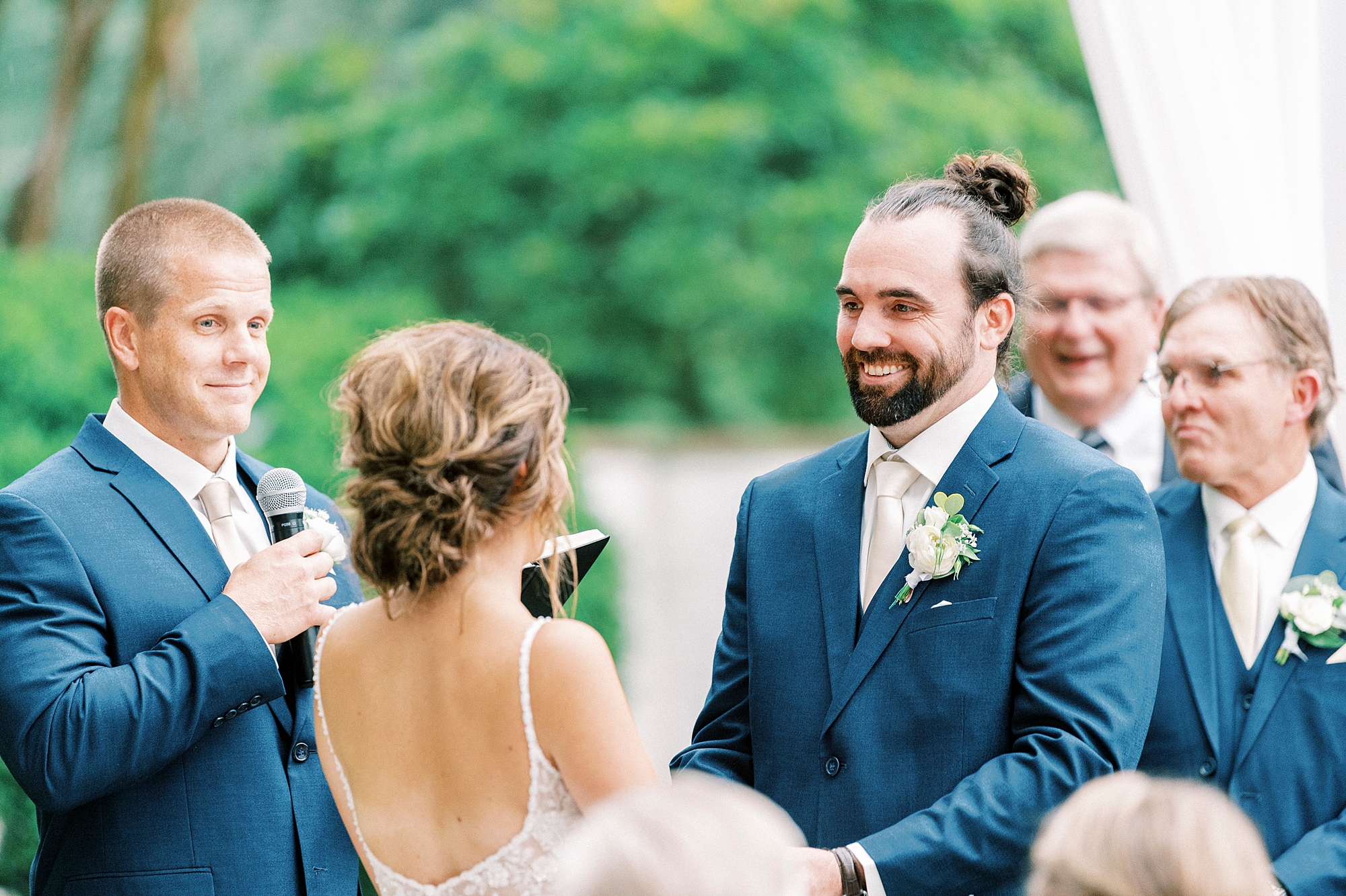groom smiles at bride during ceremony on lawn at Boxwood Estate