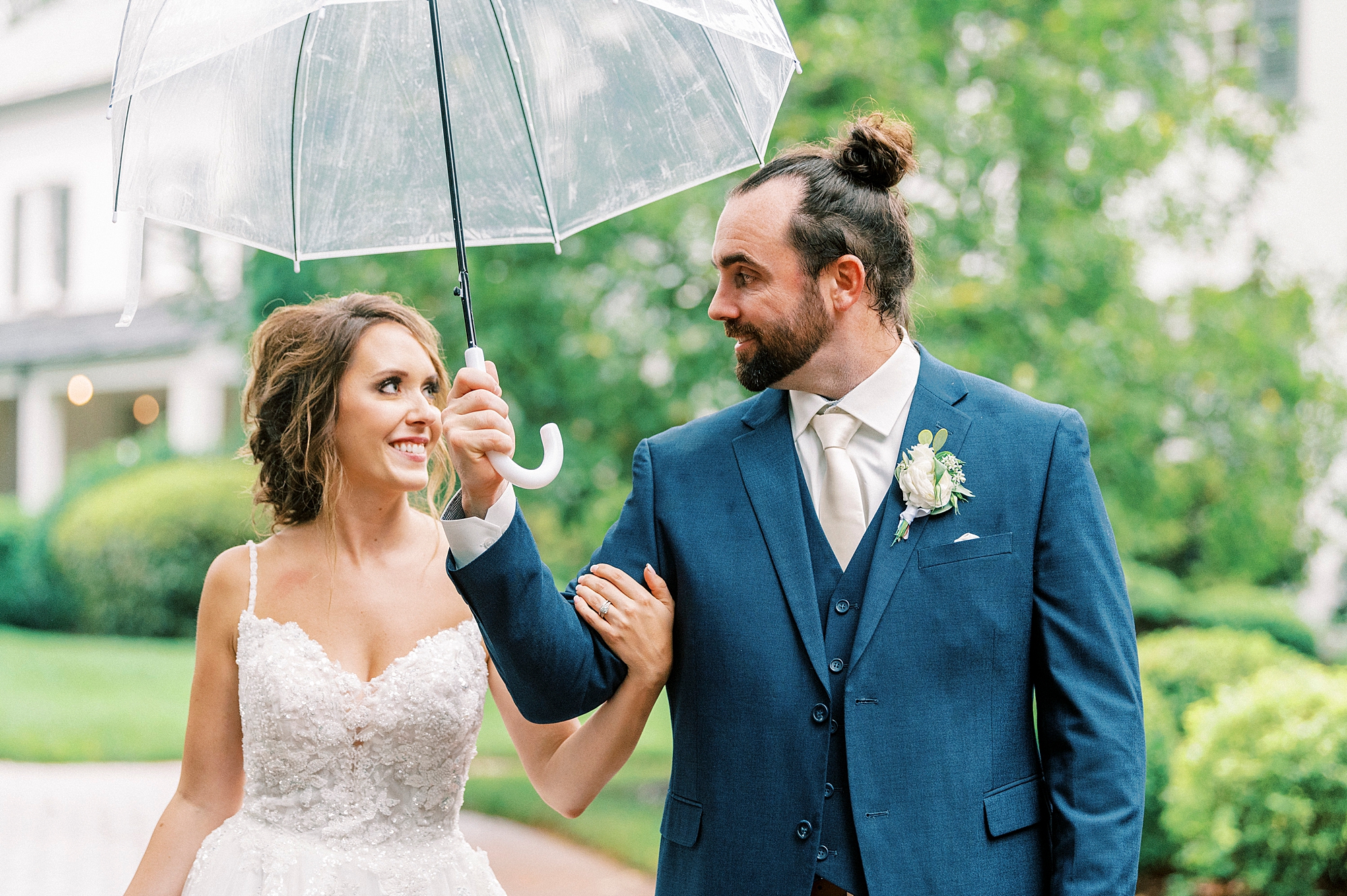 bride and groom walk under clear umbrella at Boxwood Estate