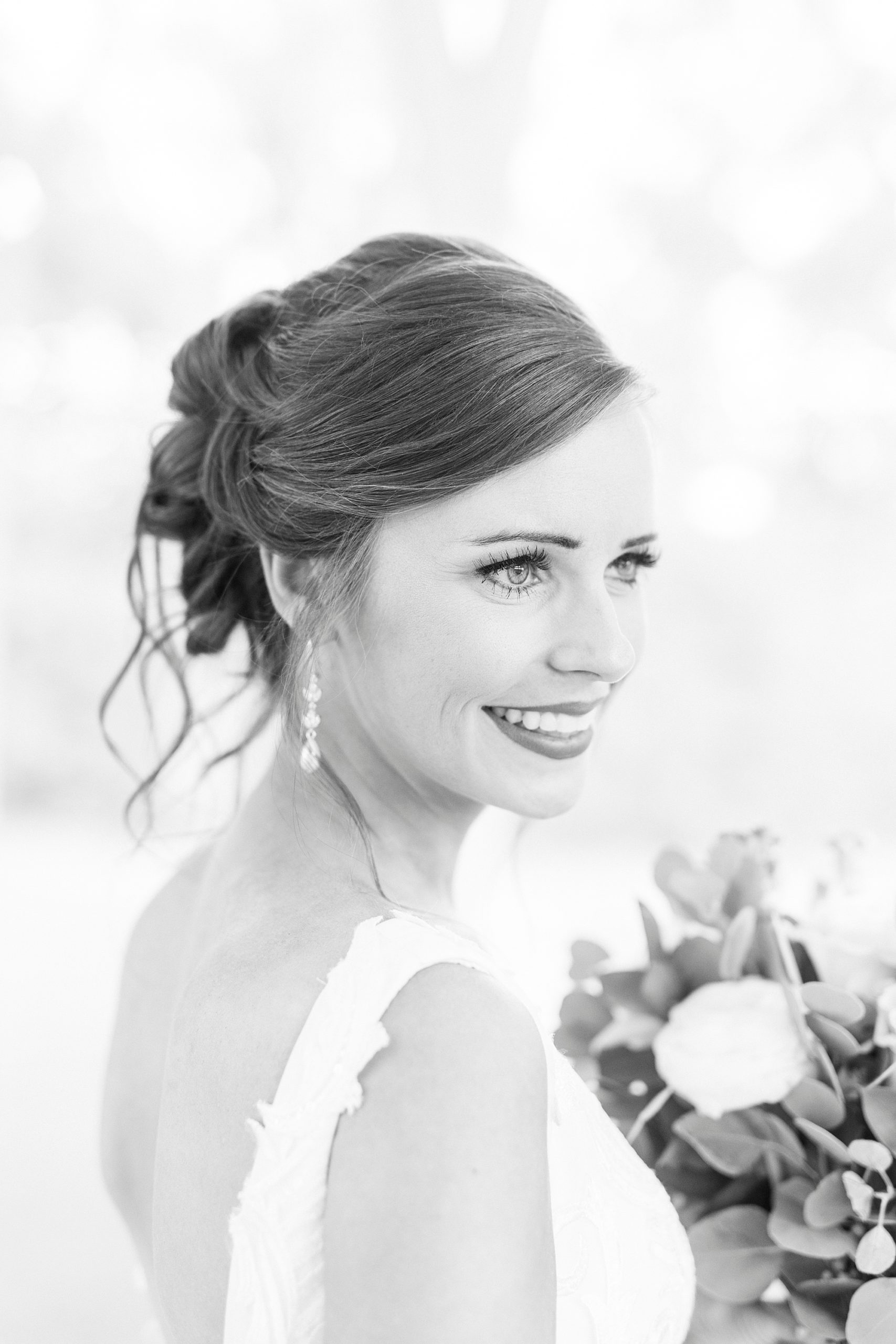 bride smiles over shoulder strap of wedding gown