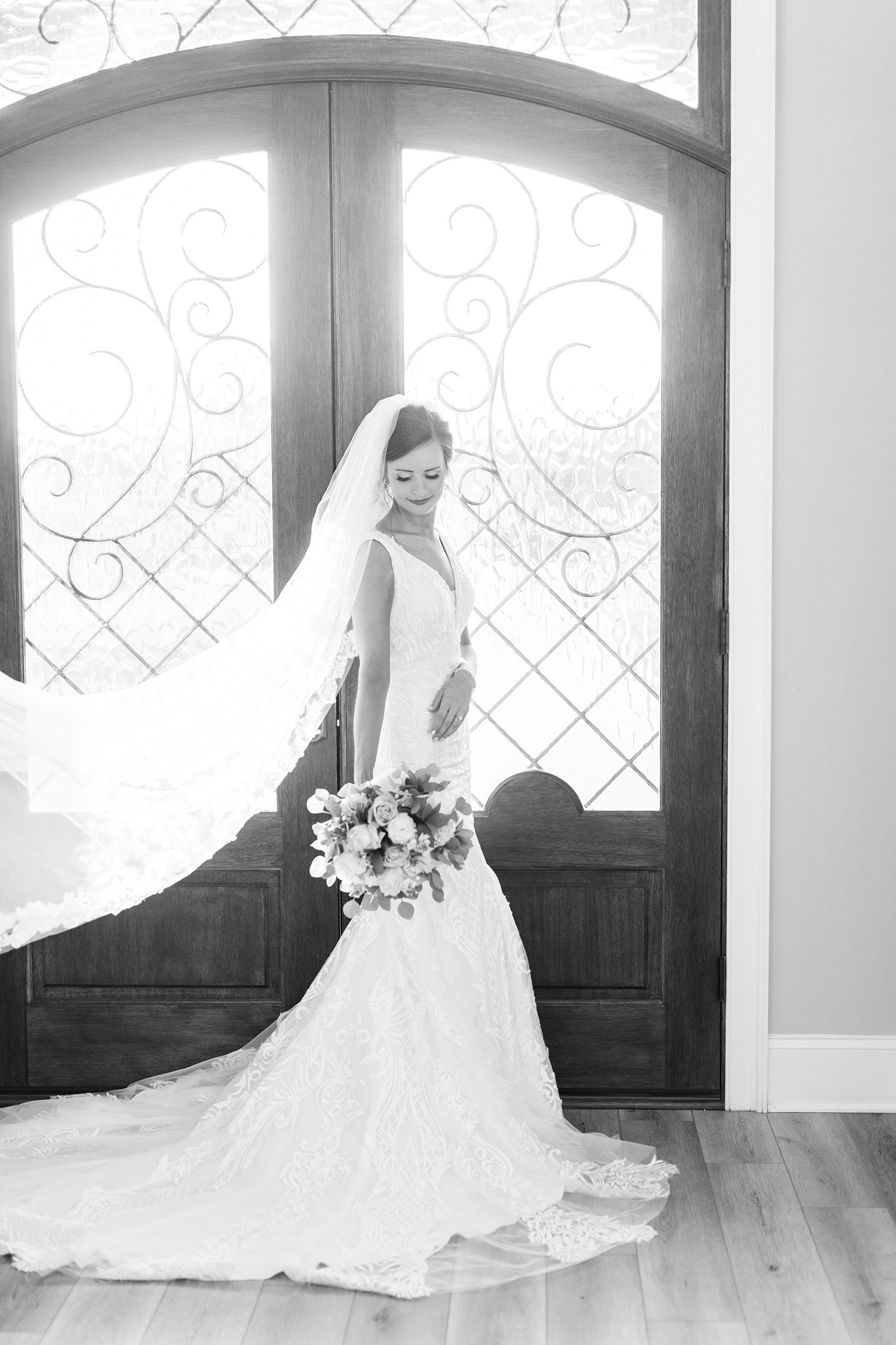 black and white portrait of bride by glass and wooden doors at Chickadee Hill Farms