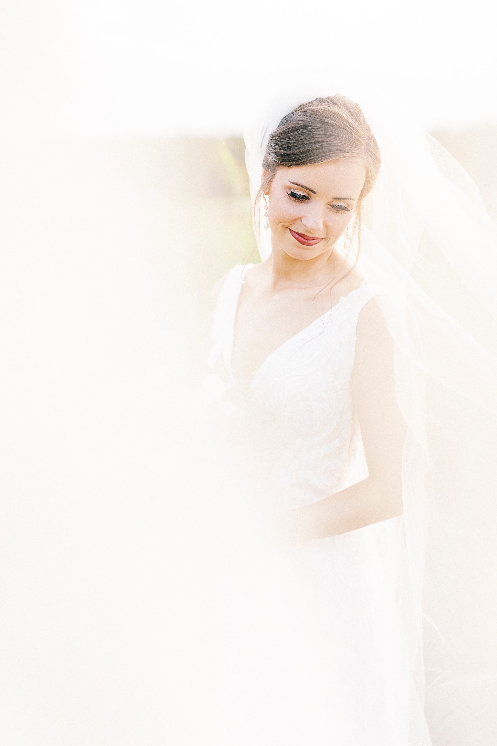 bride smiles over shoulder with veil around her