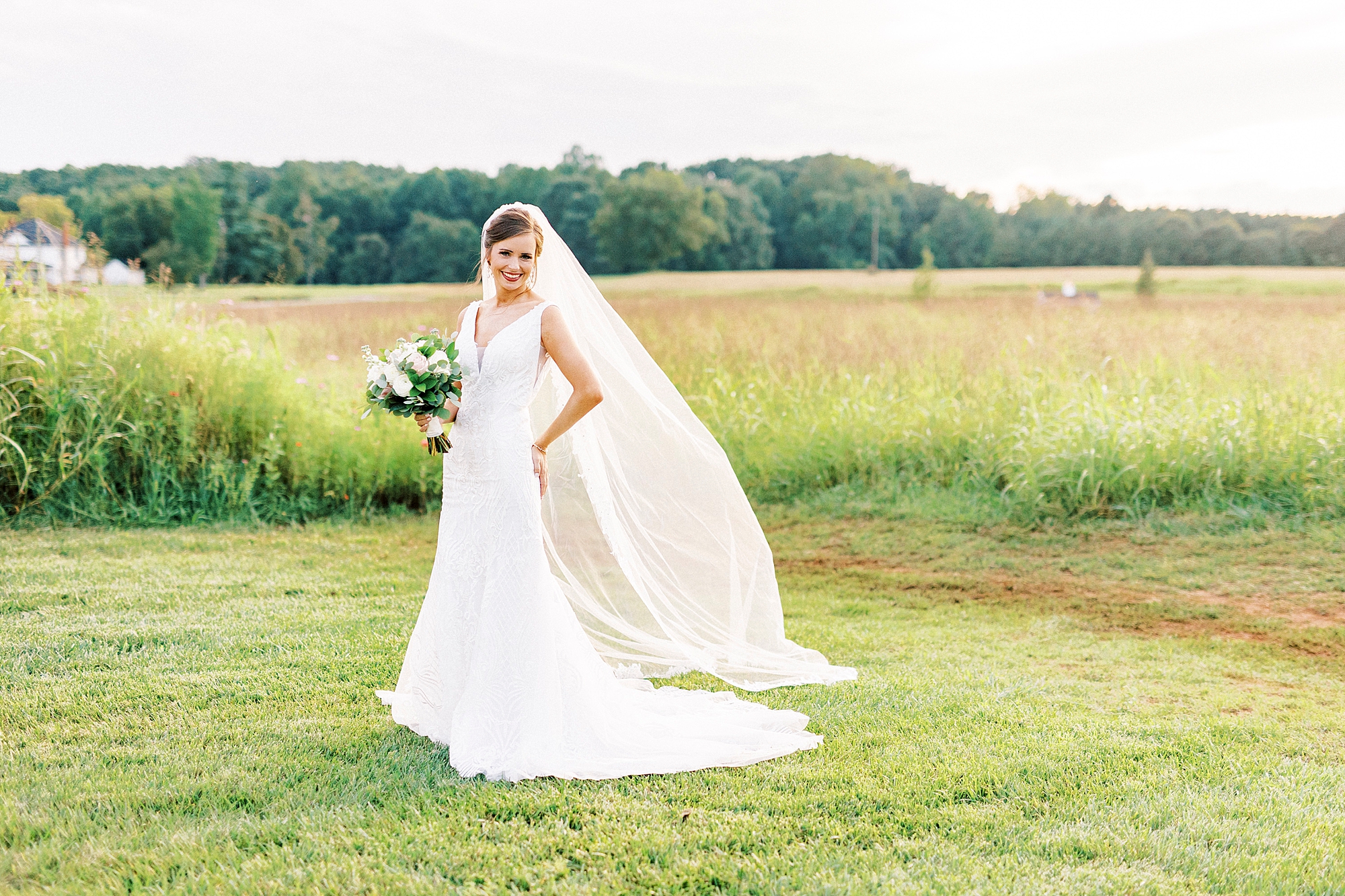 bride walks on lawn at Chickadee Hill Farms with veil floating behind her