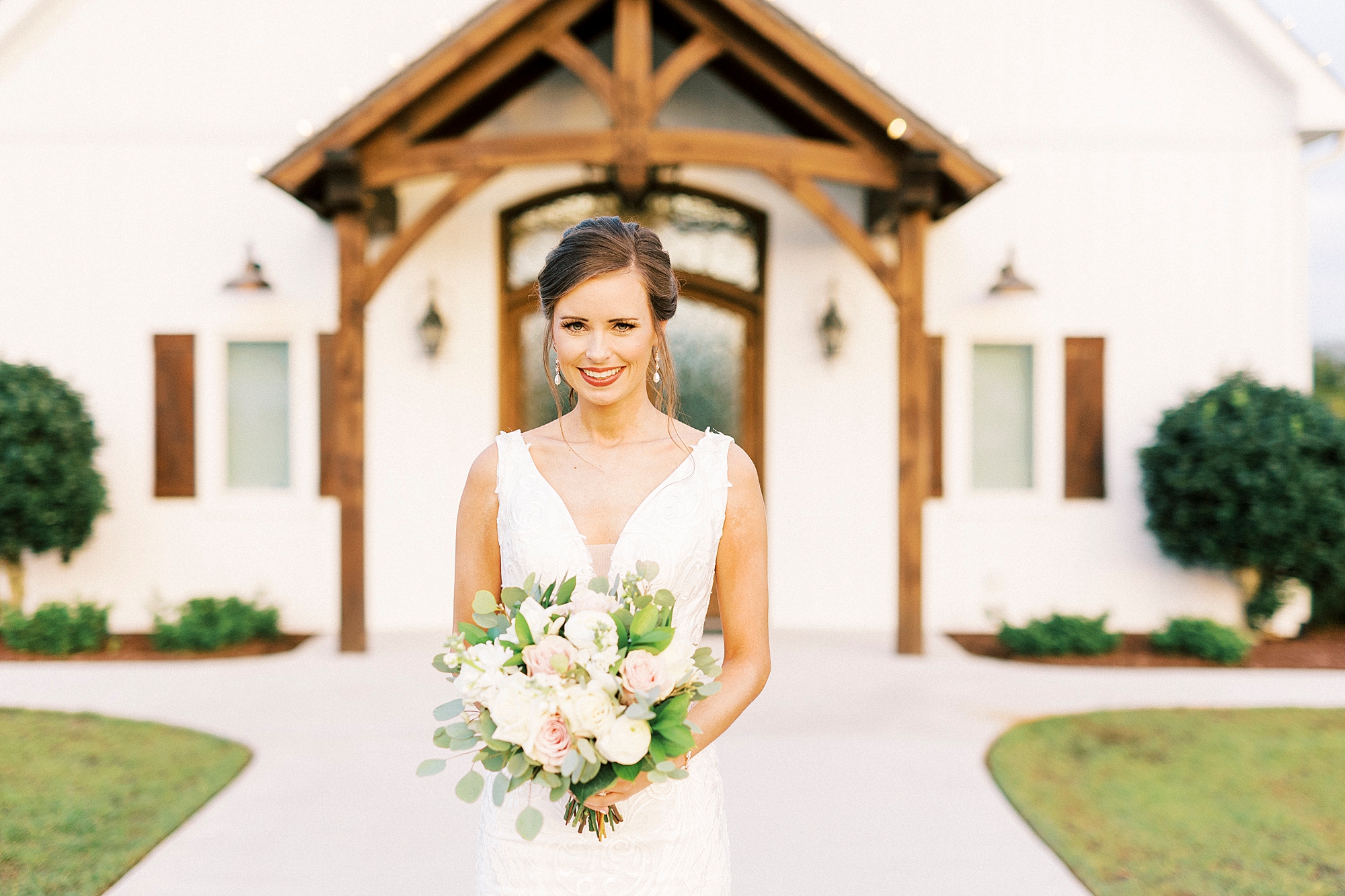 bride smiles standing outside wooden door at Chickadee Hill Farms