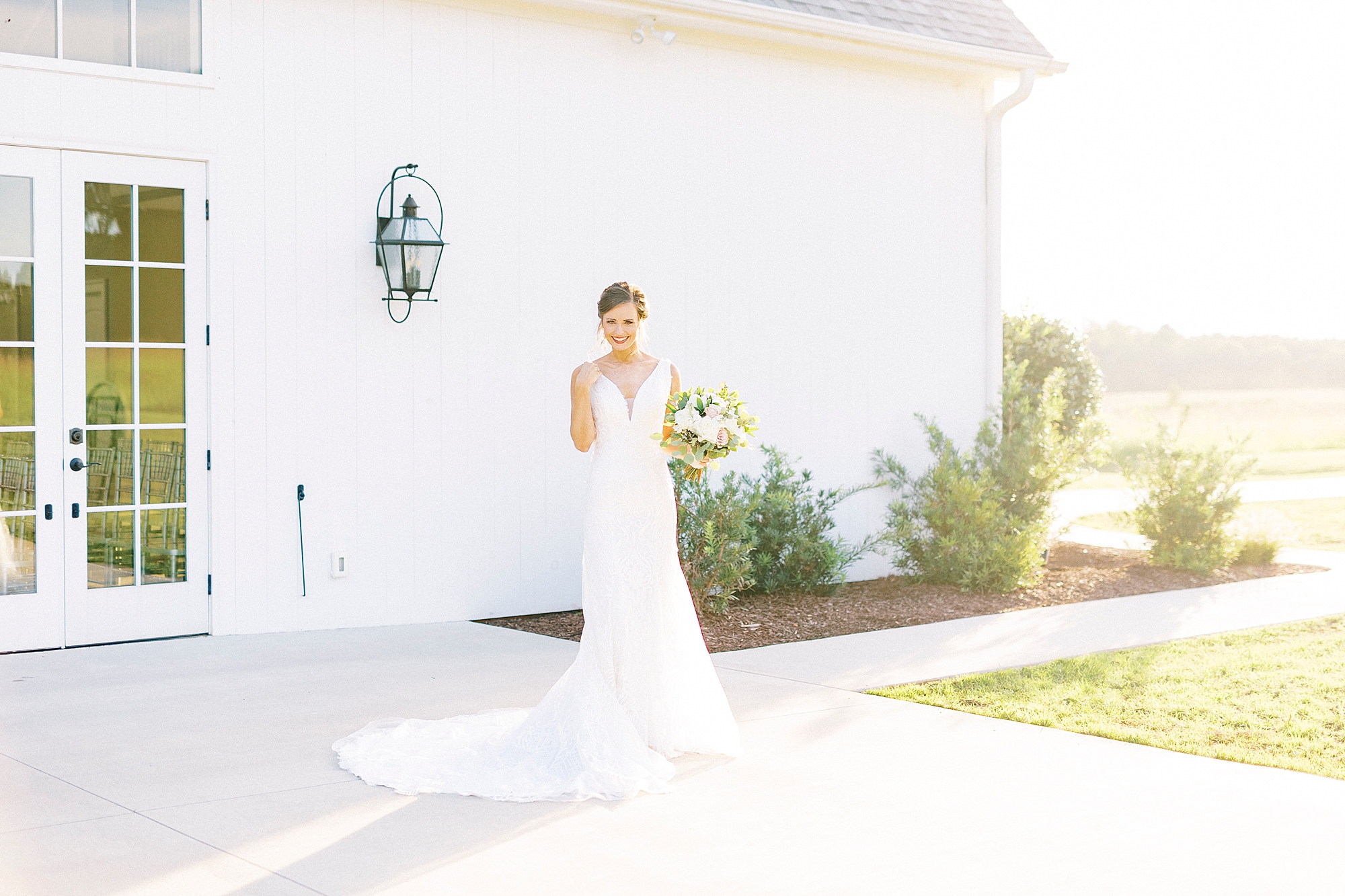 bride stands outside white barn during Chickadee Hill Farms Bridal Portraits