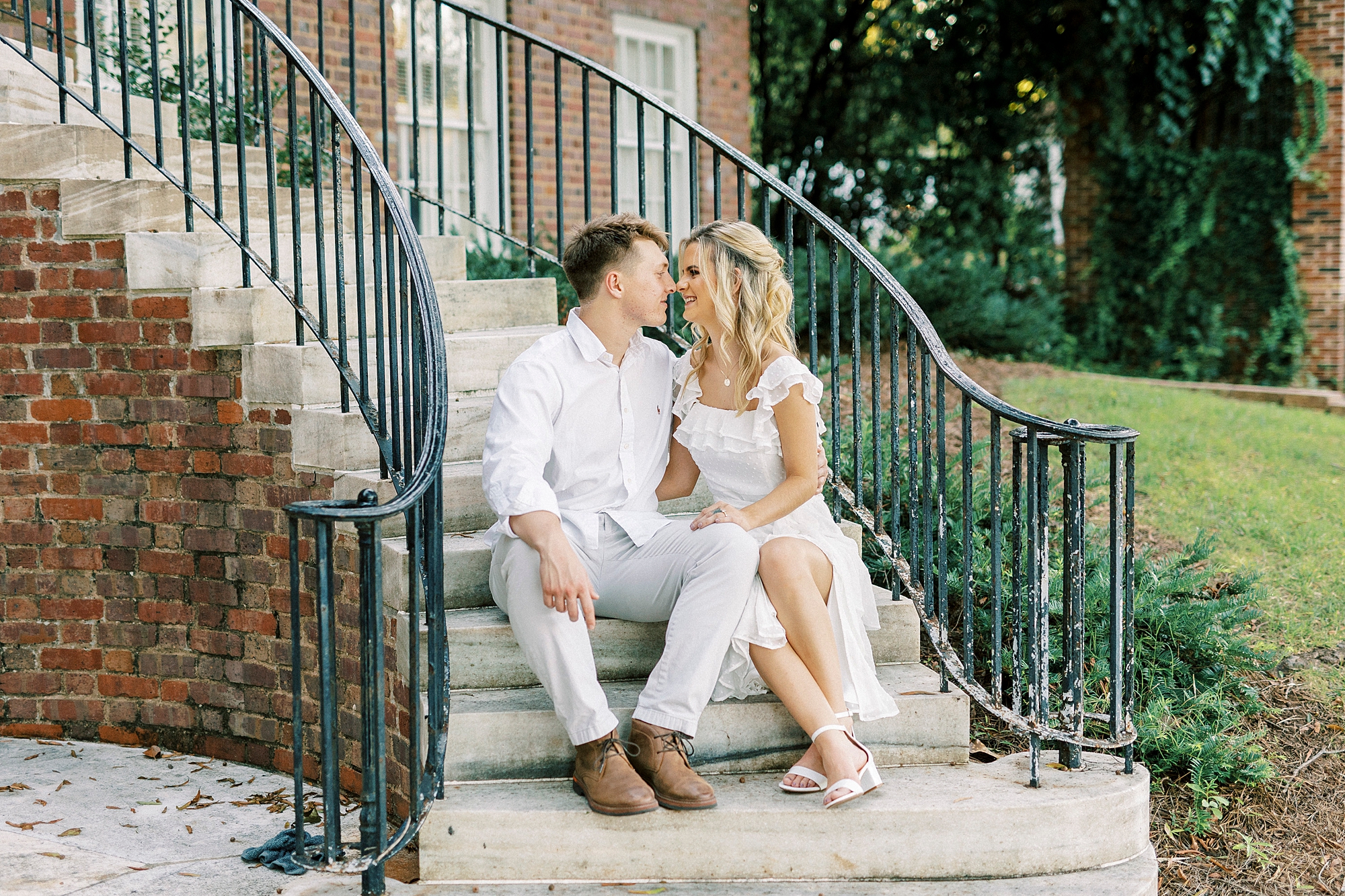 engaged couple sit together on steps during Downtown Concord engagement portraits