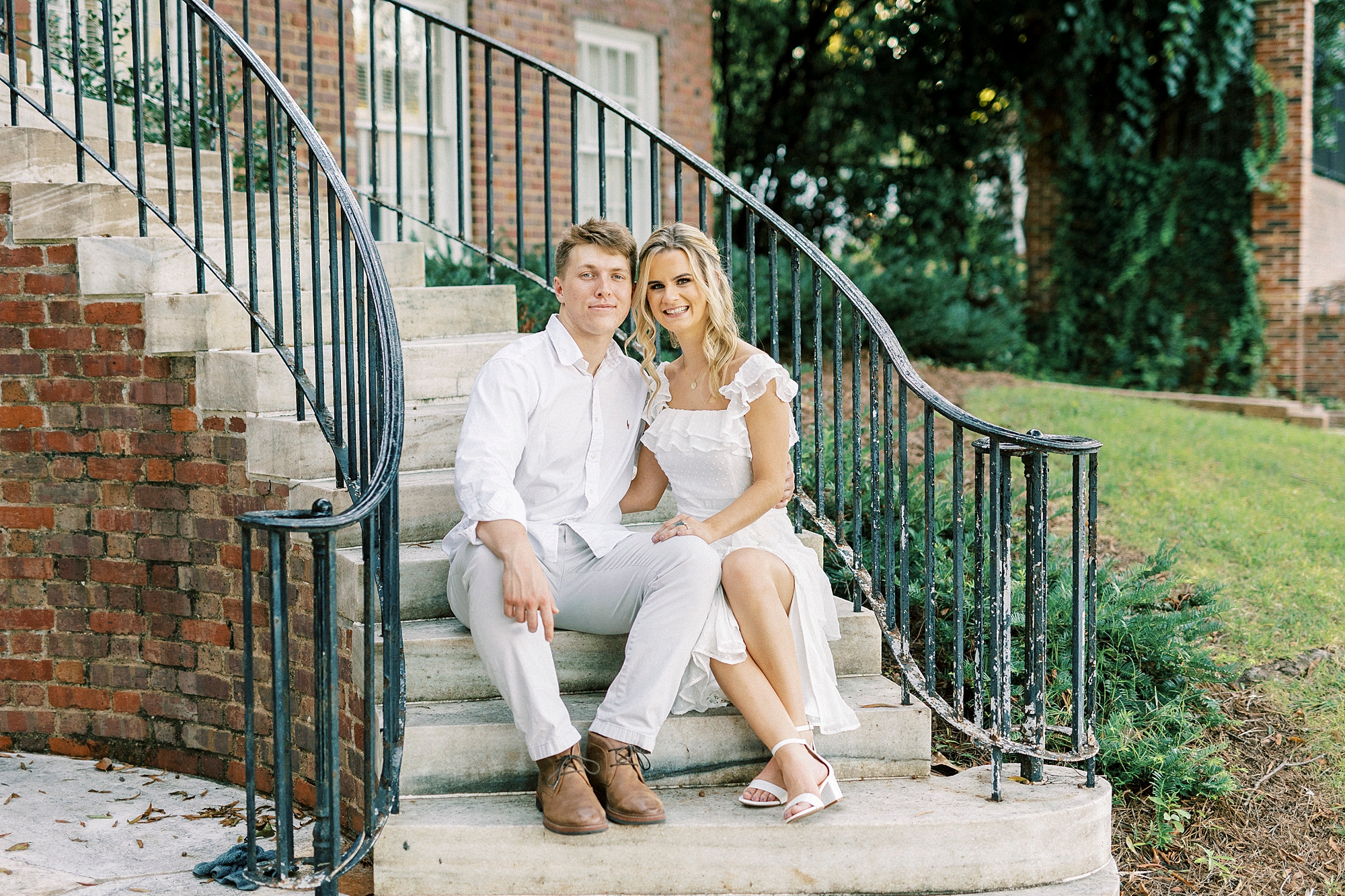 NC couple leans heads together sitting on steps during Downtown Concord engagement portraits