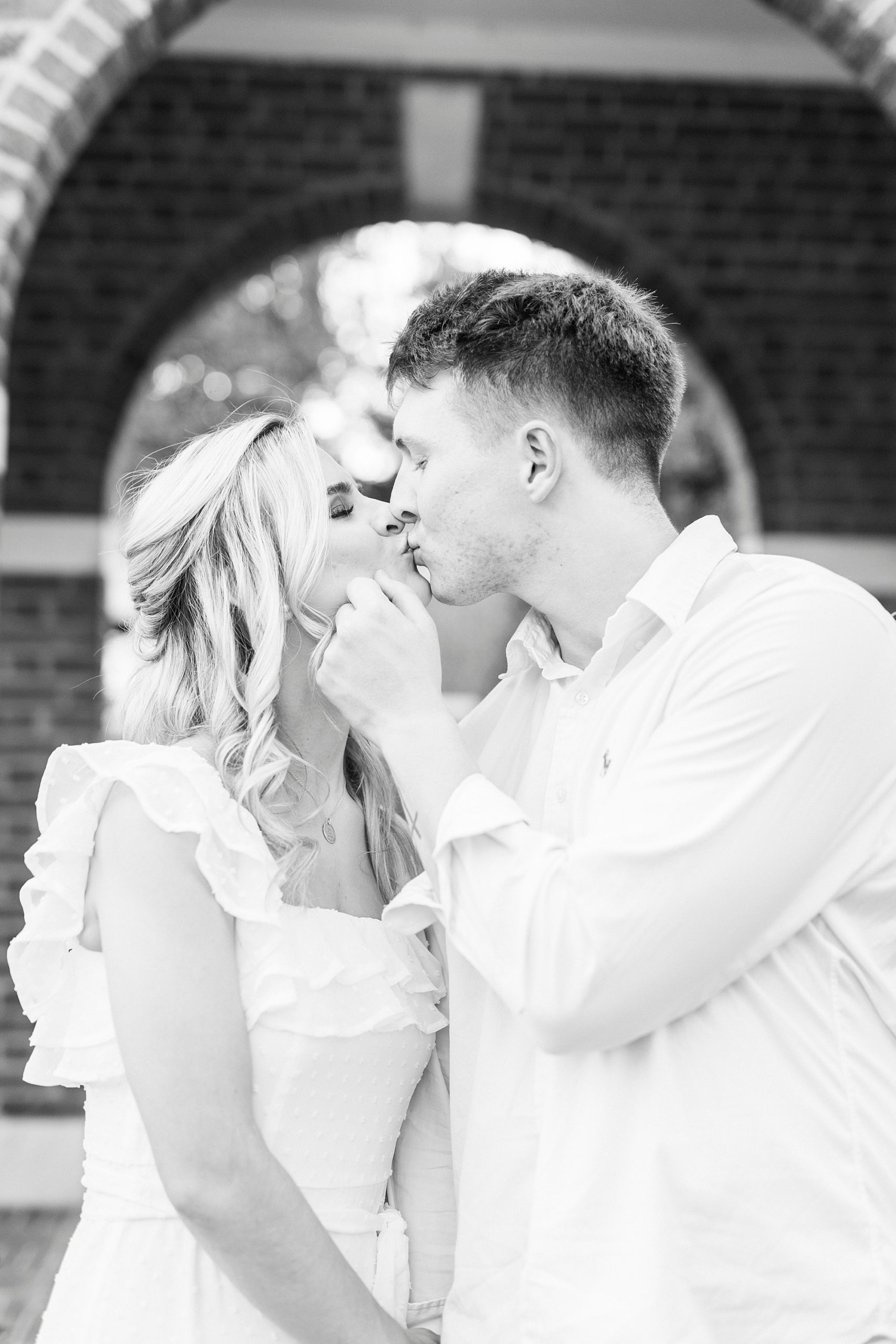 black and white portrait of man leaning to kiss fiancee
