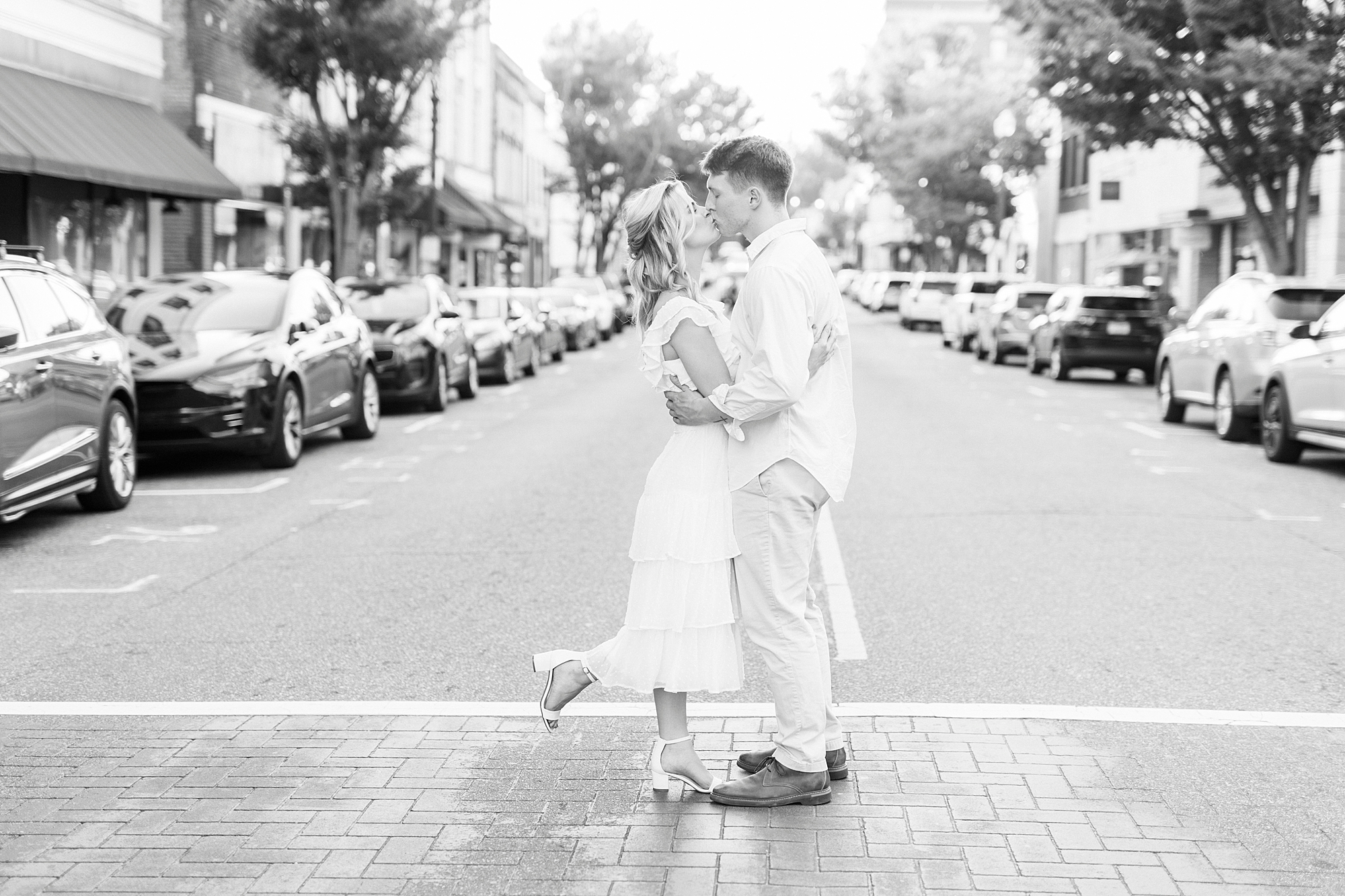 engaged couple kisses in crosswalk during Downtown Concord engagement portraits