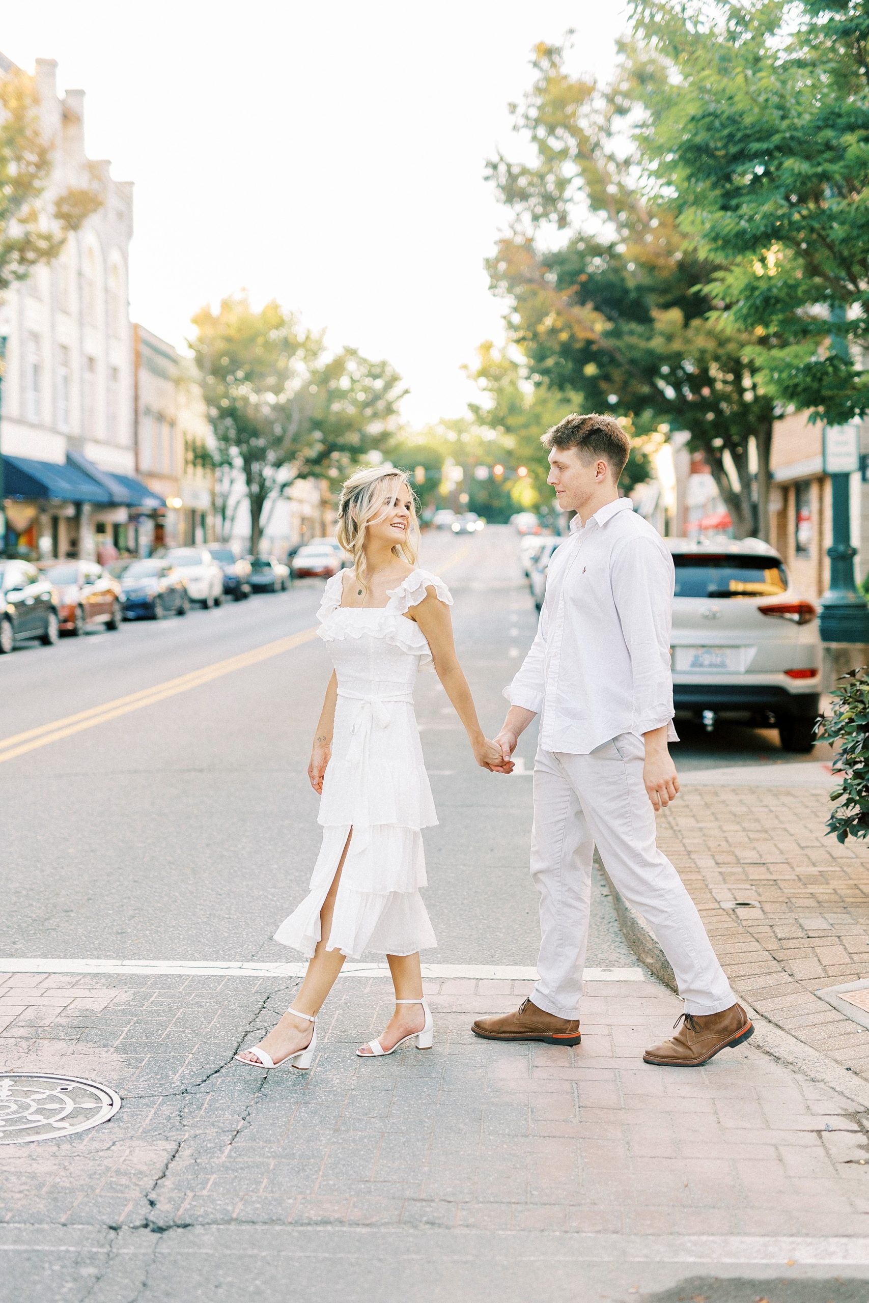 couple walks across crosswalk in formal outfits 