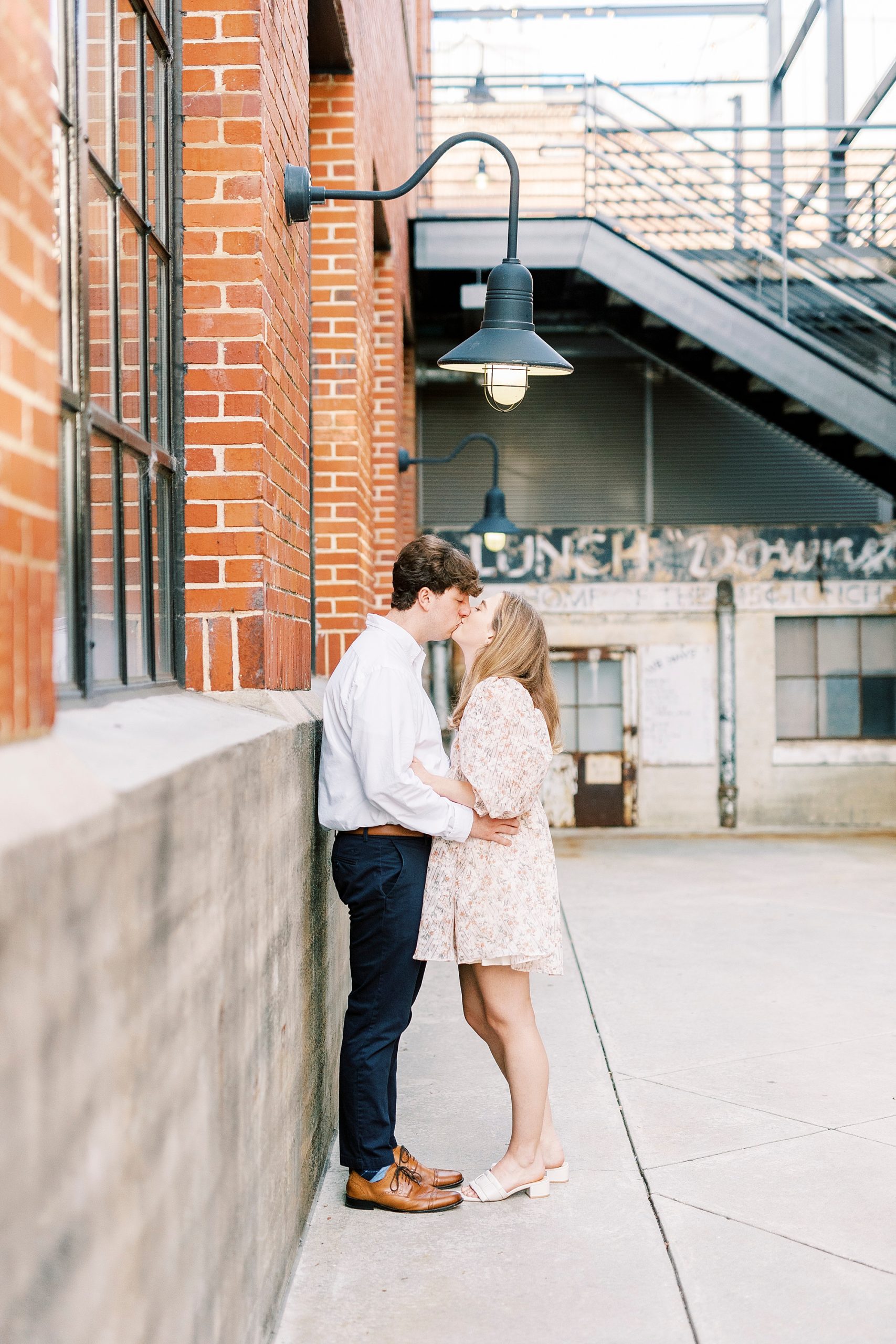 couple leans against brick wall at American Tobacco Campus