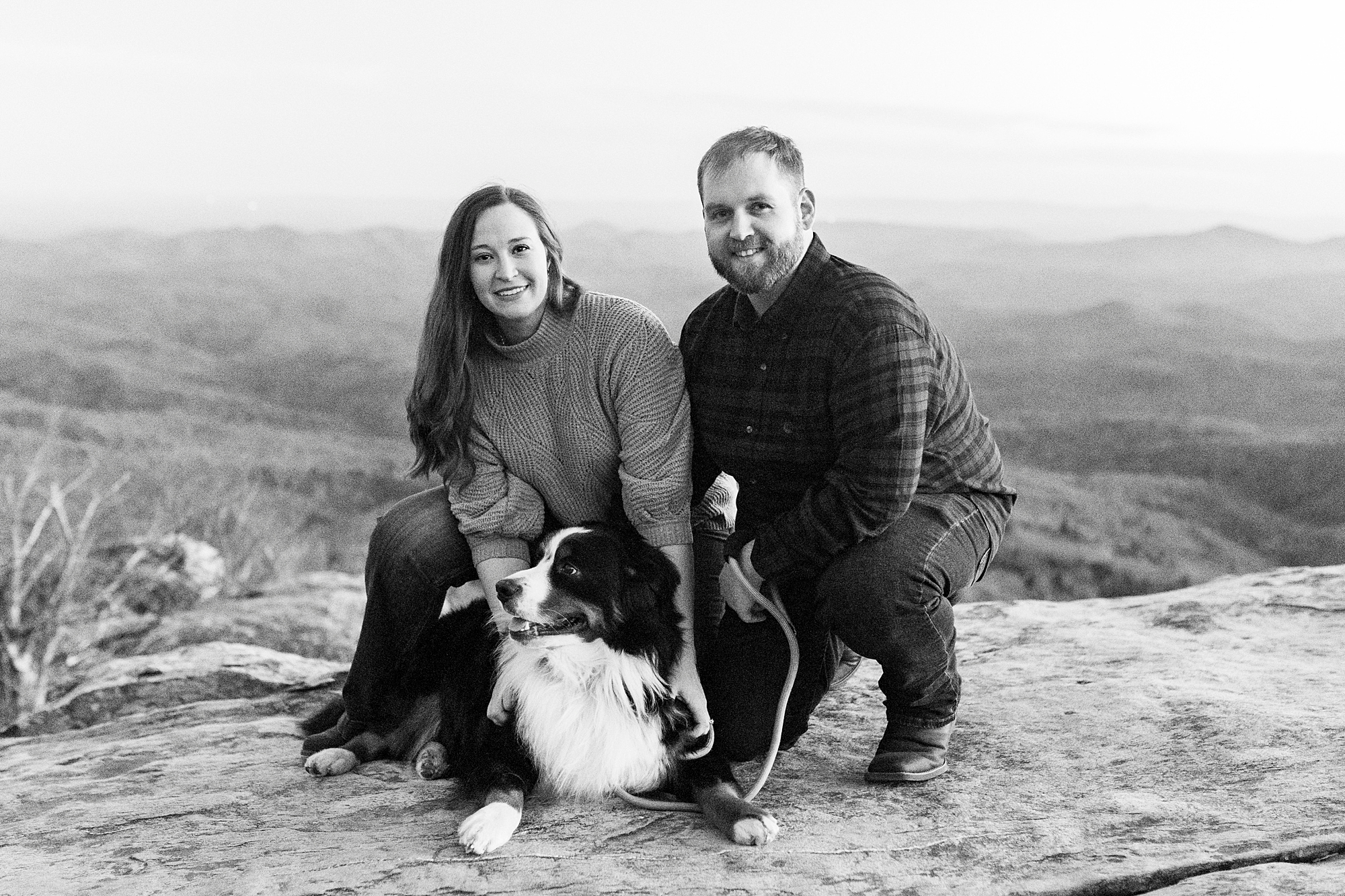 couple poses with Bernese Mountain Dog atop Rough Ridge in the Blue Ridge Parkway