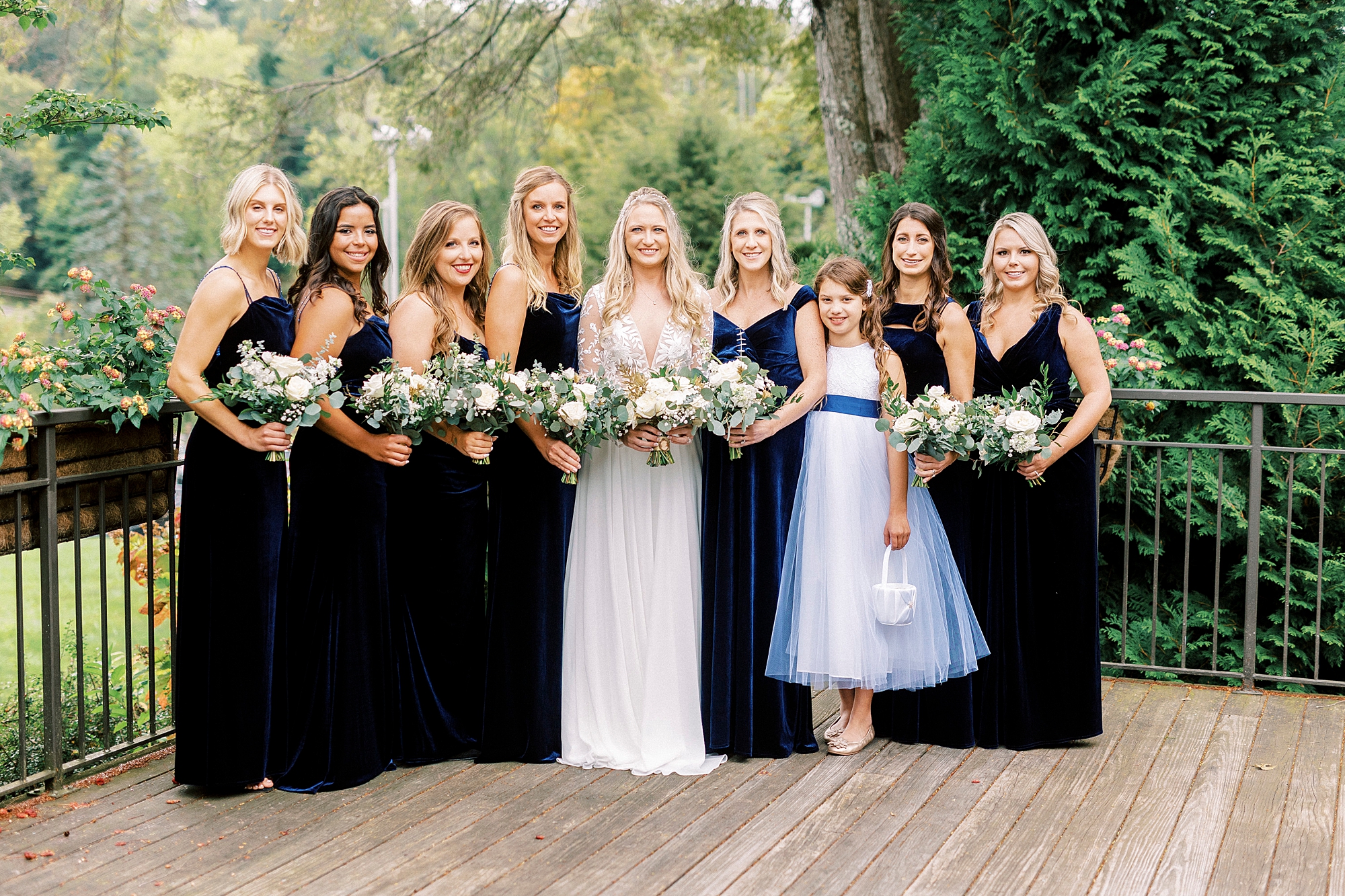bride poses with bridesmaids in black gowns on balcony at Chetola Resort
