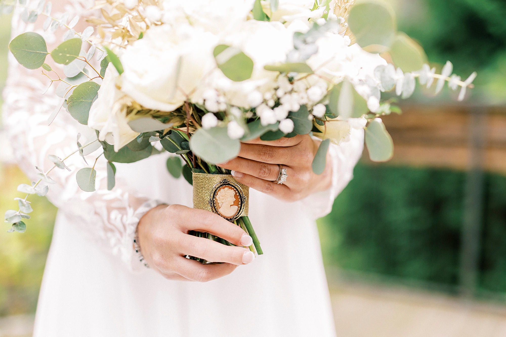bride holds bouquet with broach on stem