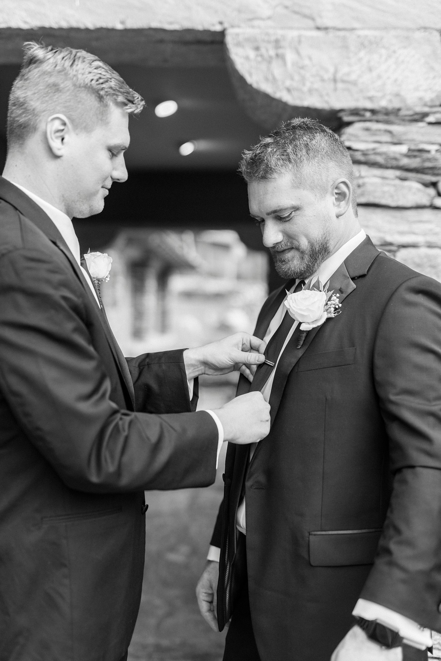 groomsman helps groom with tie before NC wedding