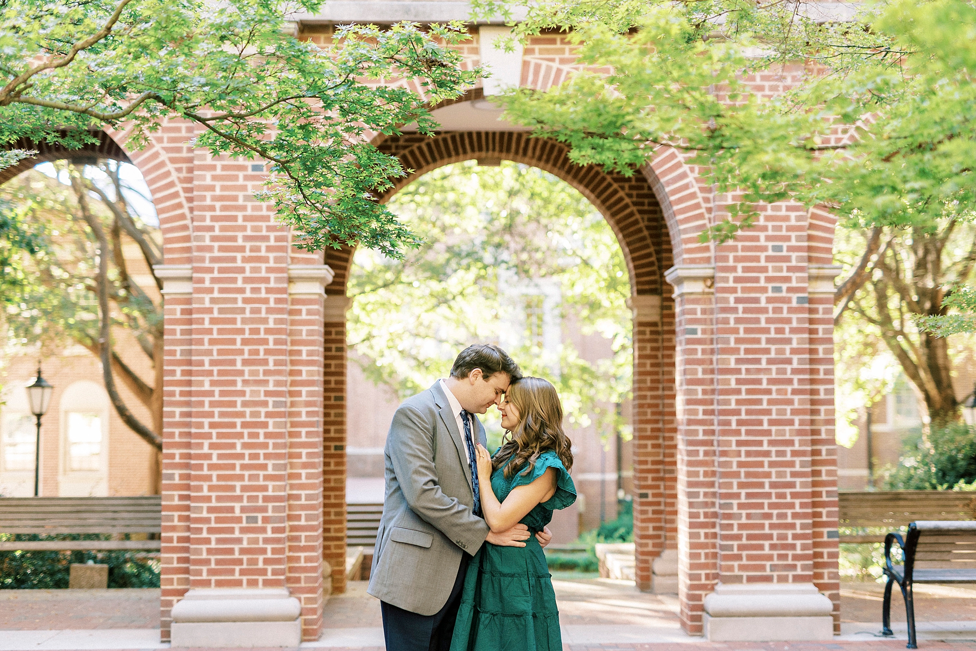 engaged couple hugs under brick archway during Downtown Davidson engagement session