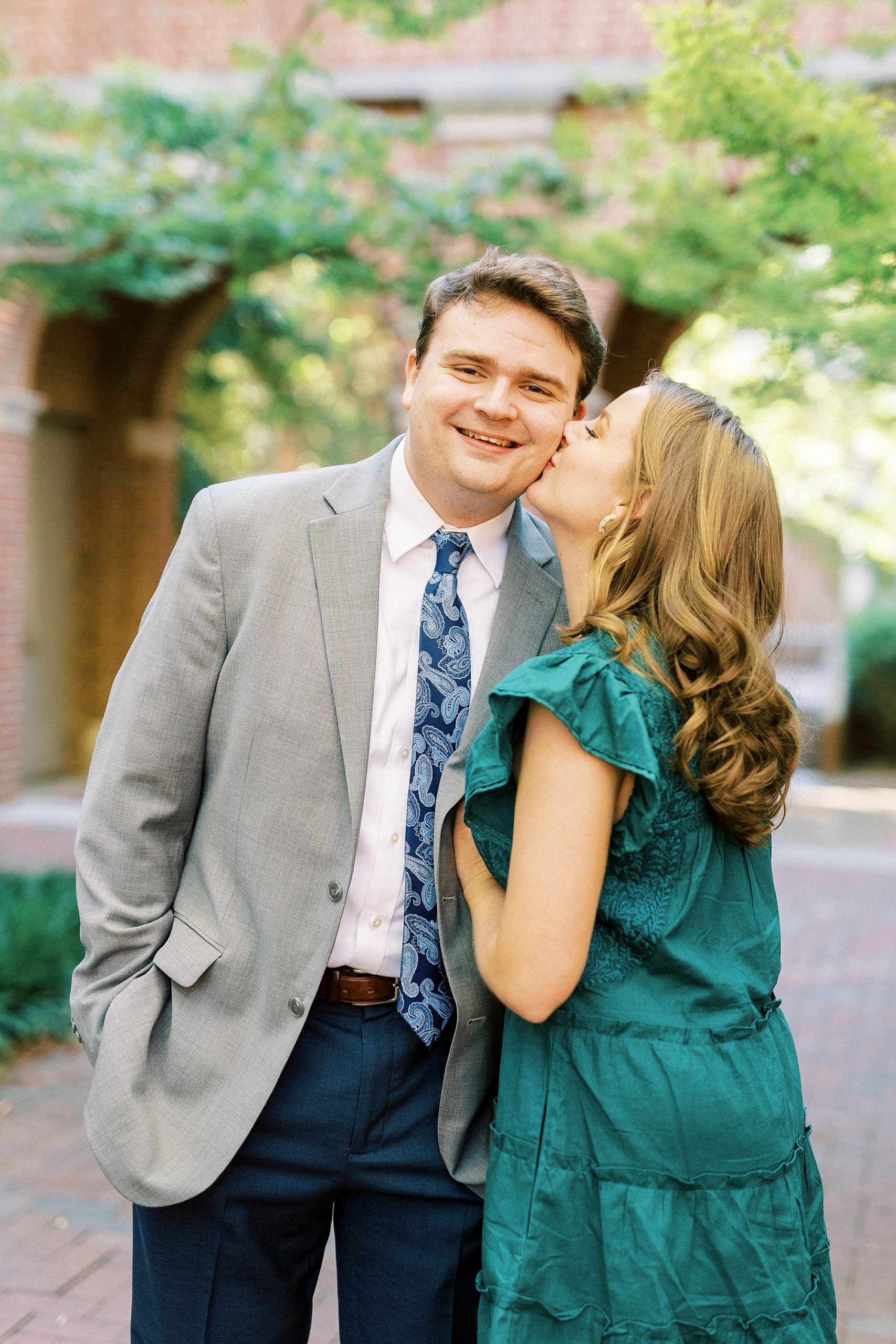 bride leans up kissing groom's cheek in Downtown Davidson