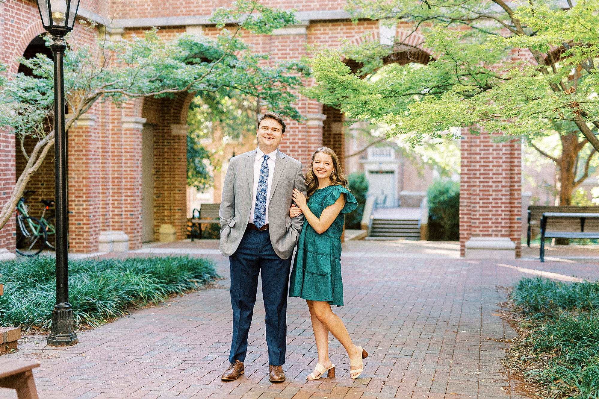 bride in teal dress hugs groom's arm during NC engagement photos 