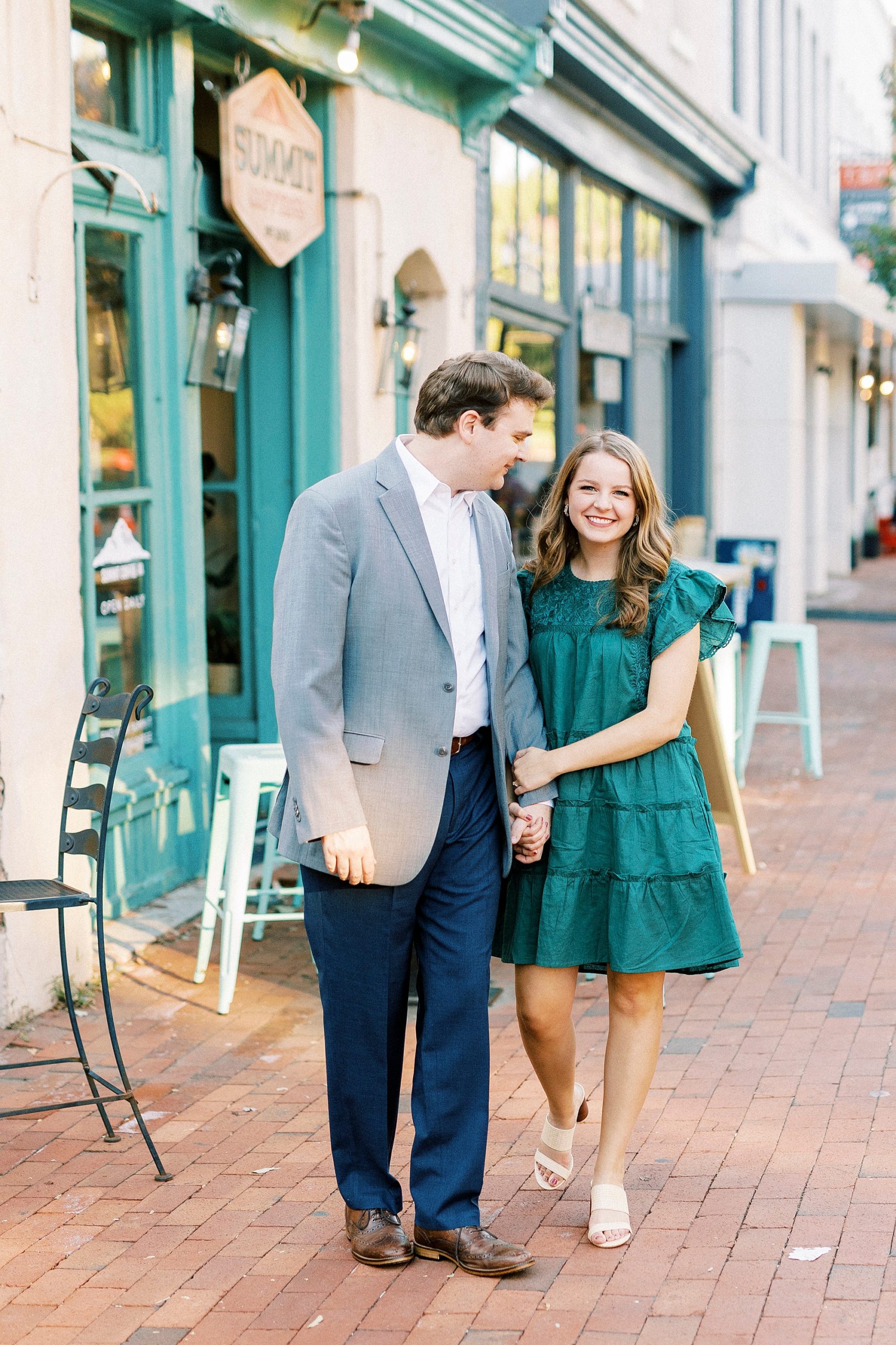 bride and groom walk outside shop with teal decor in Downtown Davidson