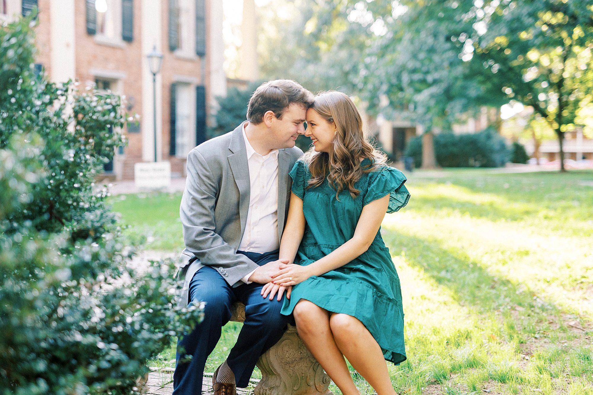 bride and groom sit on lawn during Downtown Davidson engagement session