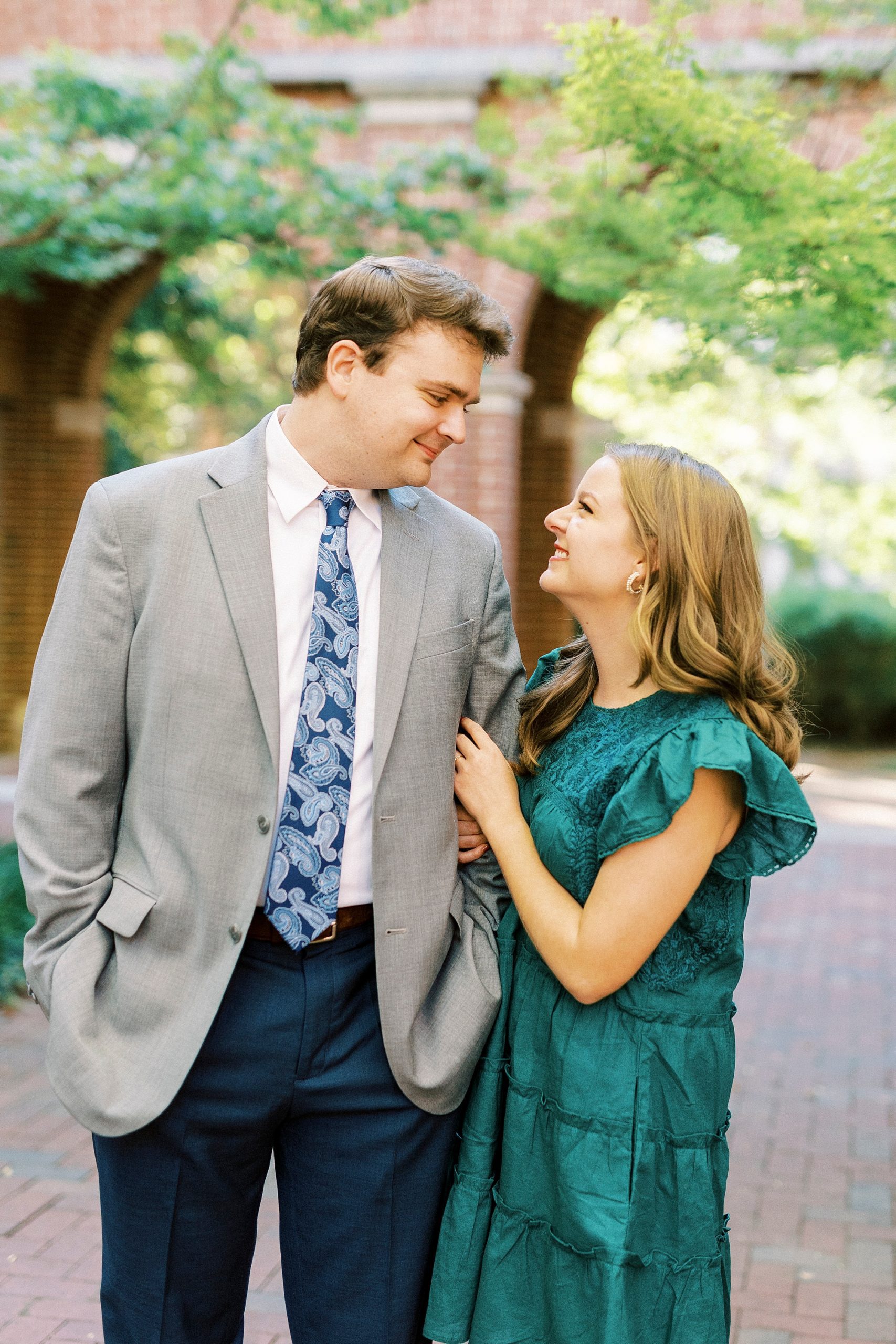 bride in teal dress smiles up at groom during NC engagement photos 