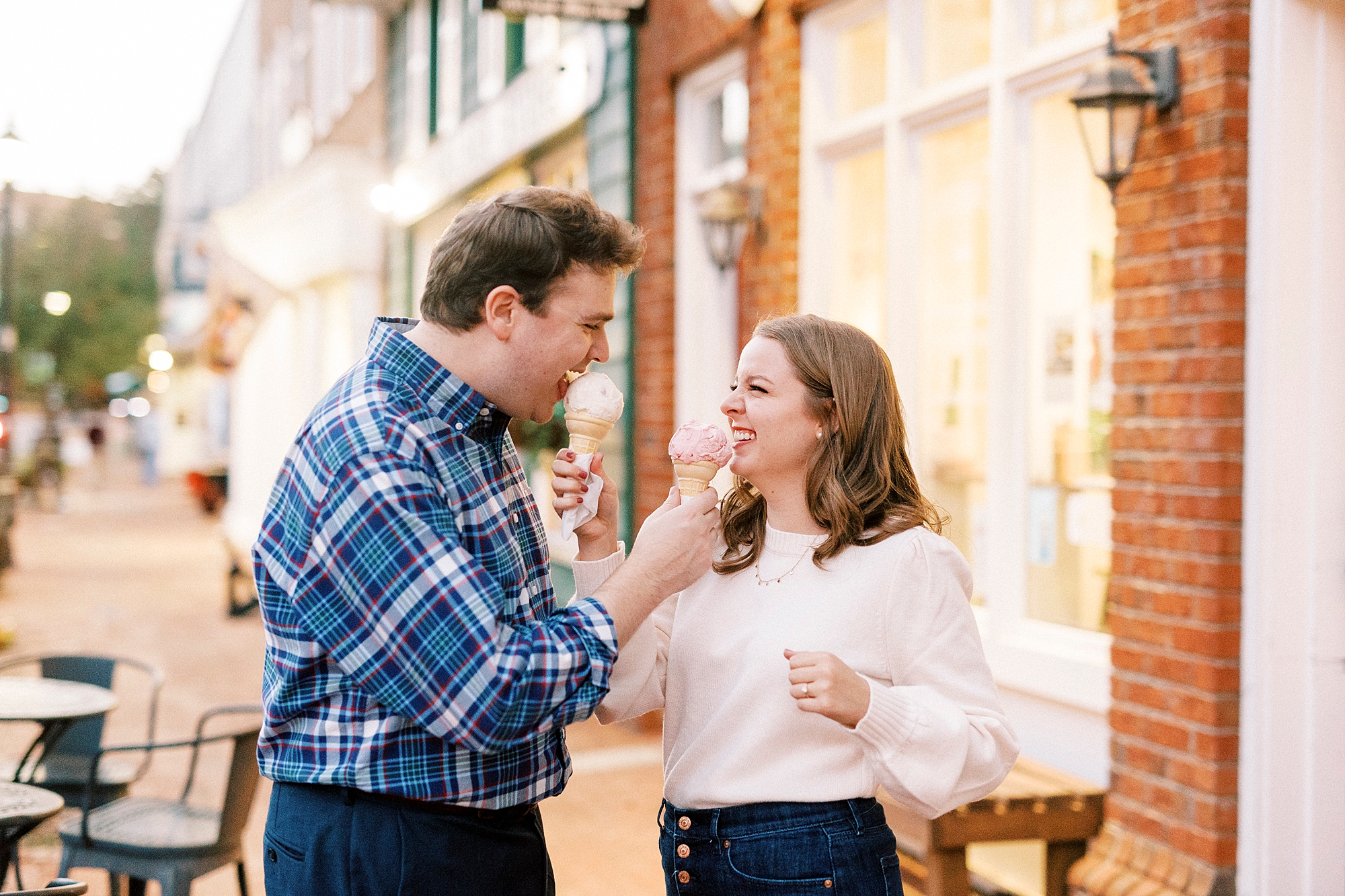 bride and groom feed each other ice cream during engagement portraits 