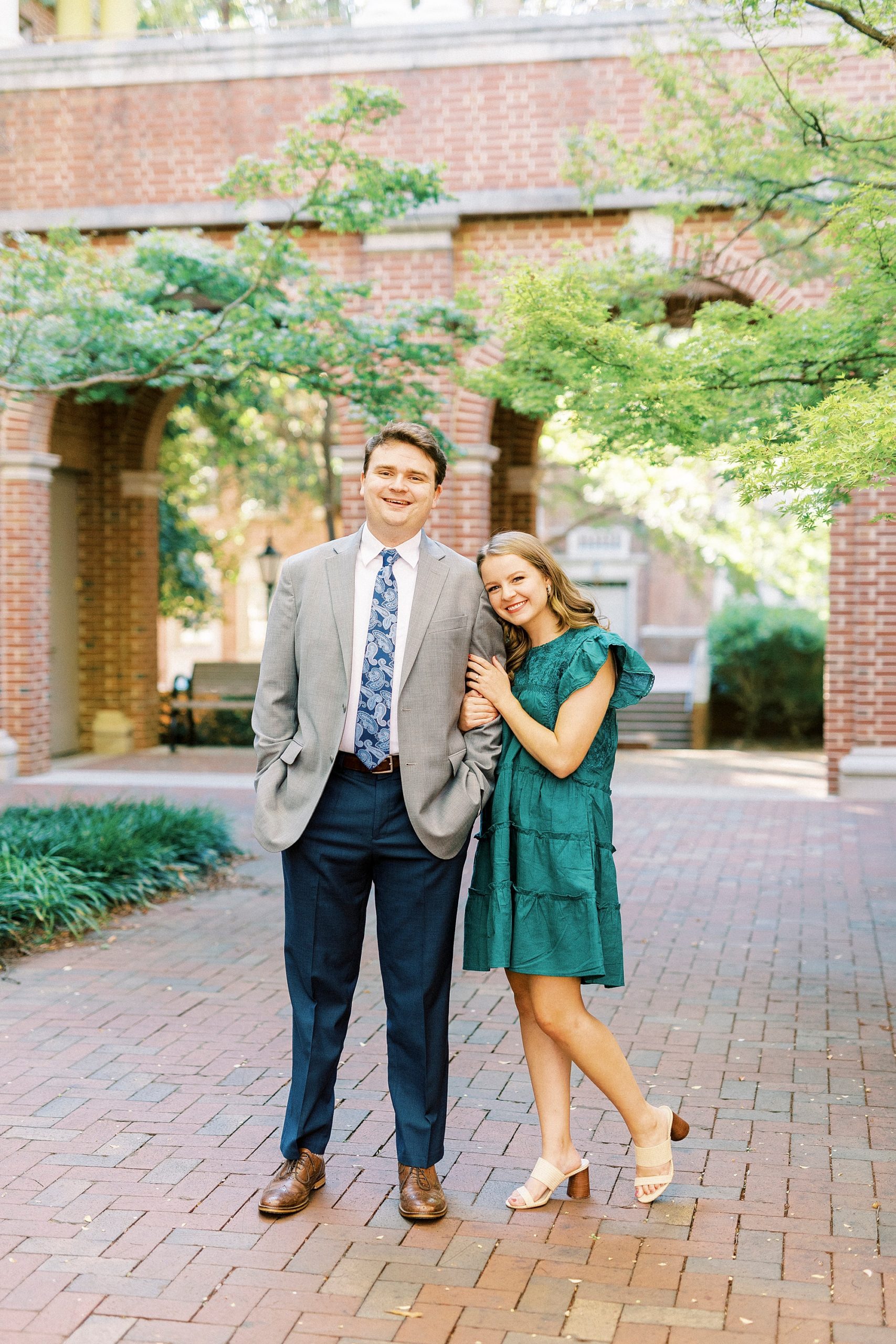 bride leans on groom's arm during Downtown Davidson engagement photos