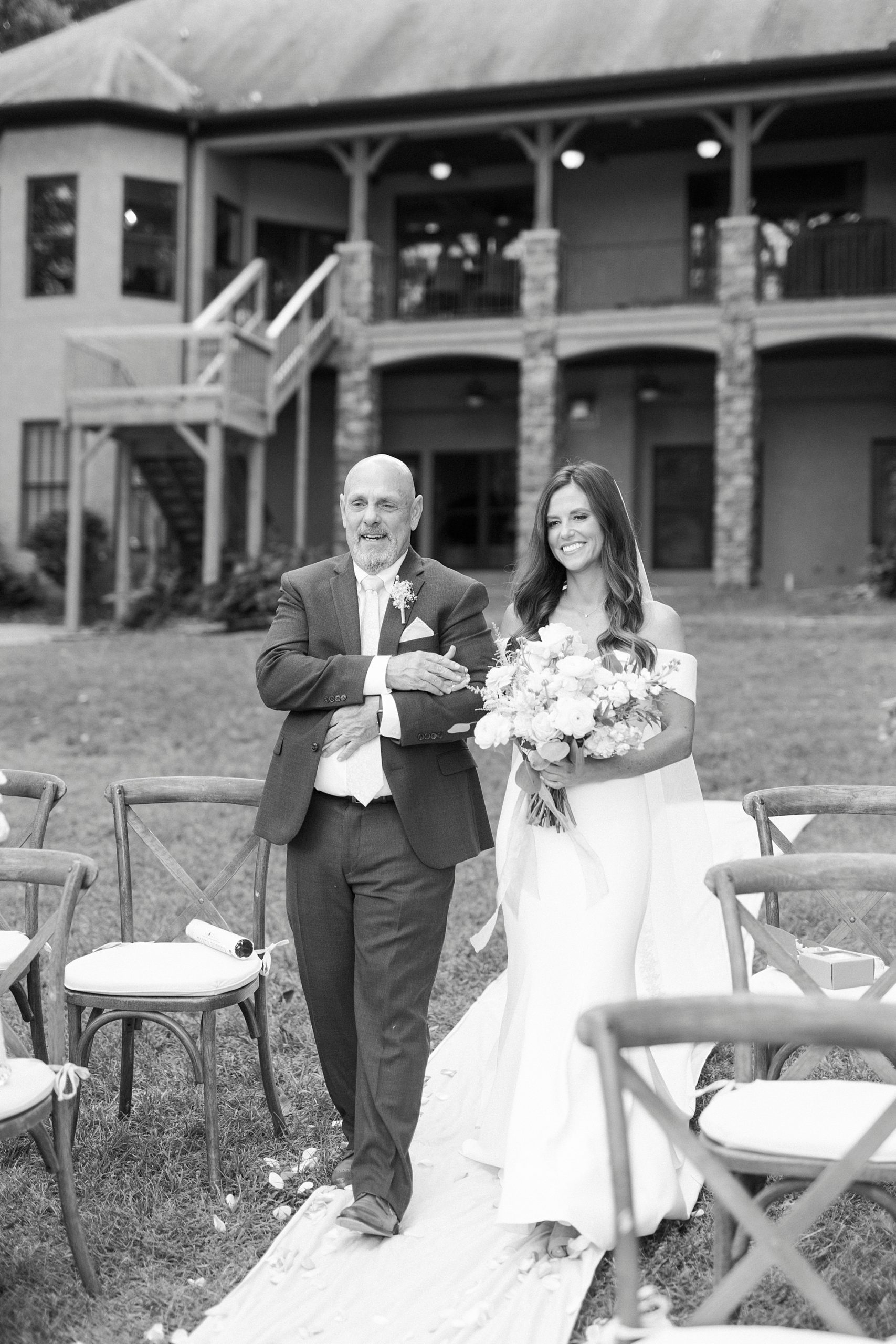 black and white portrait of bride walking down aisle with dad