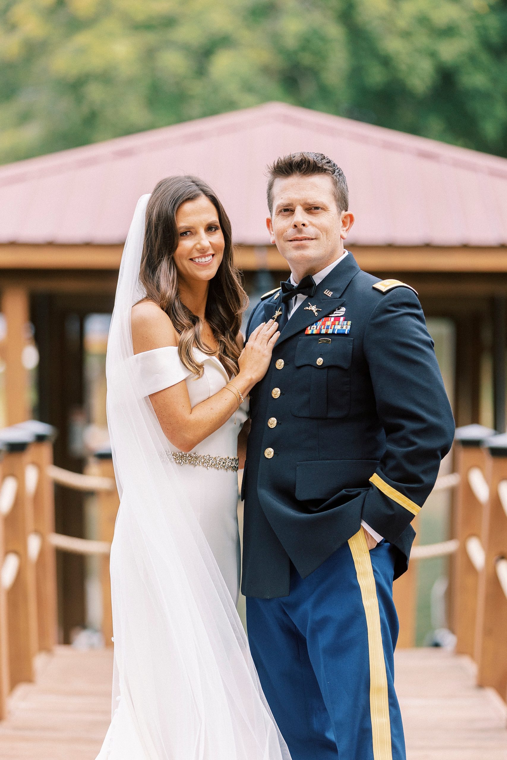bride hugs groom in military dress blues on wooden dock at Lake Norman
