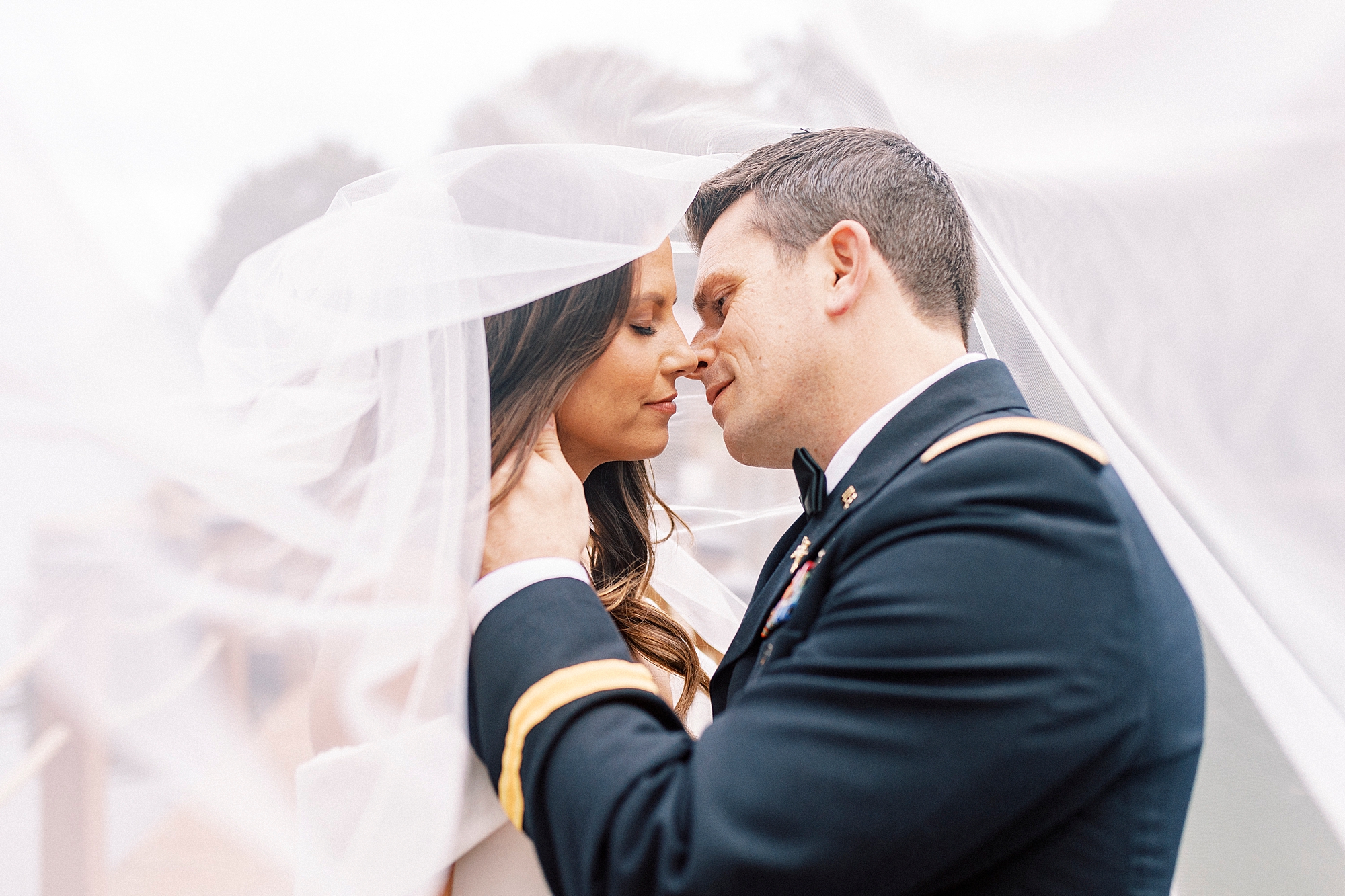 groom leans to kiss bride with her veil over them at Lake Norman