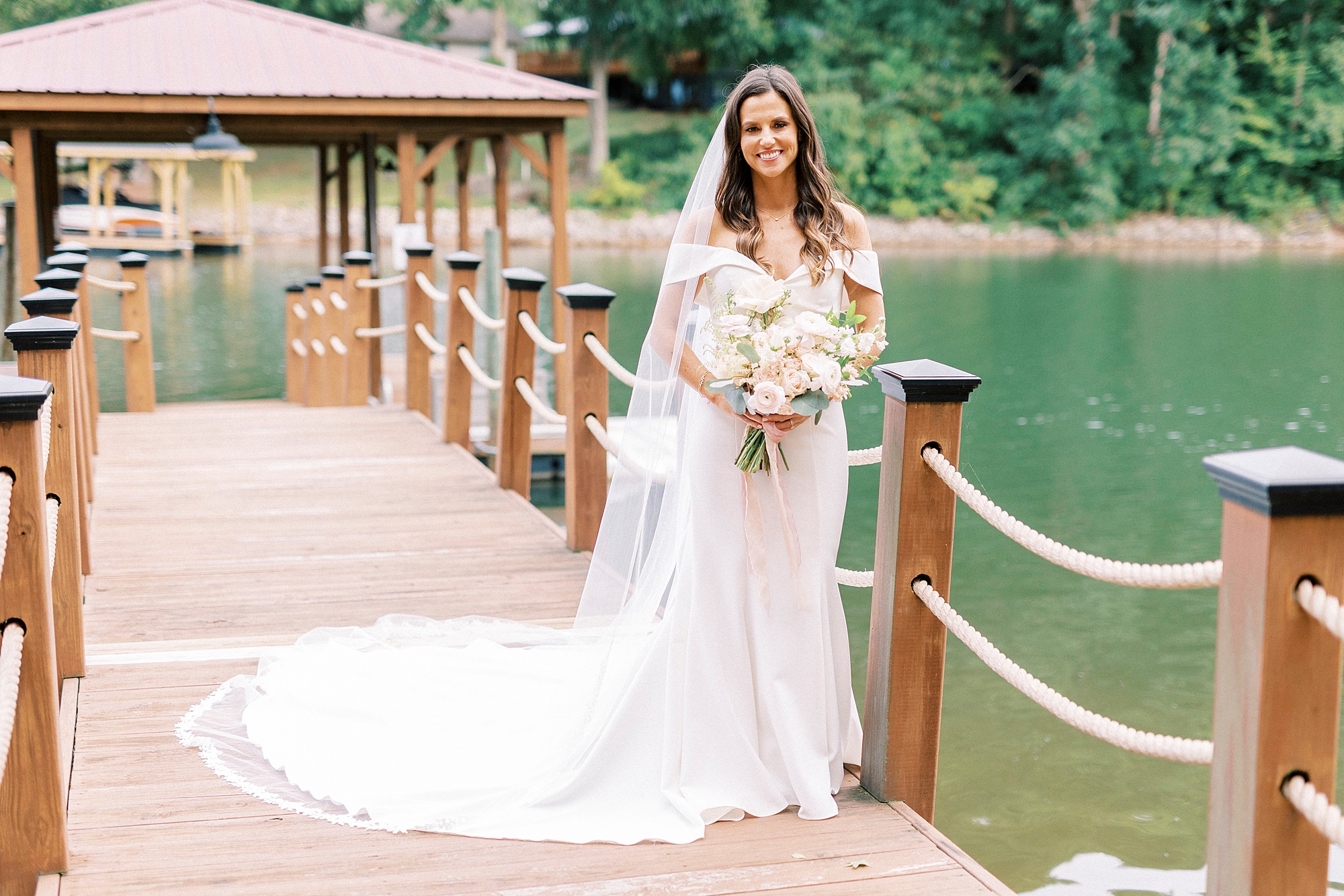 bride poses on wooden dock overlooking Lake Norman