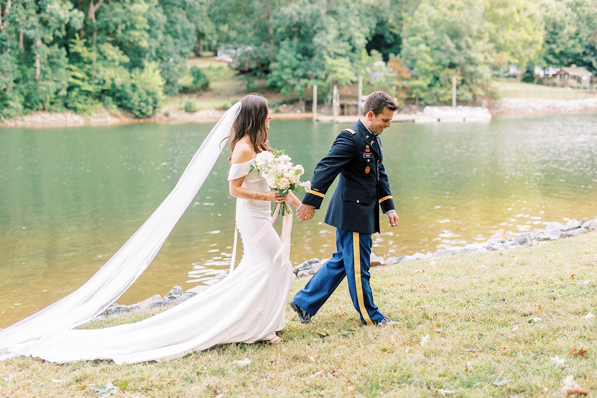 newlyweds hold hands walking on lawn of Lake Norman home 