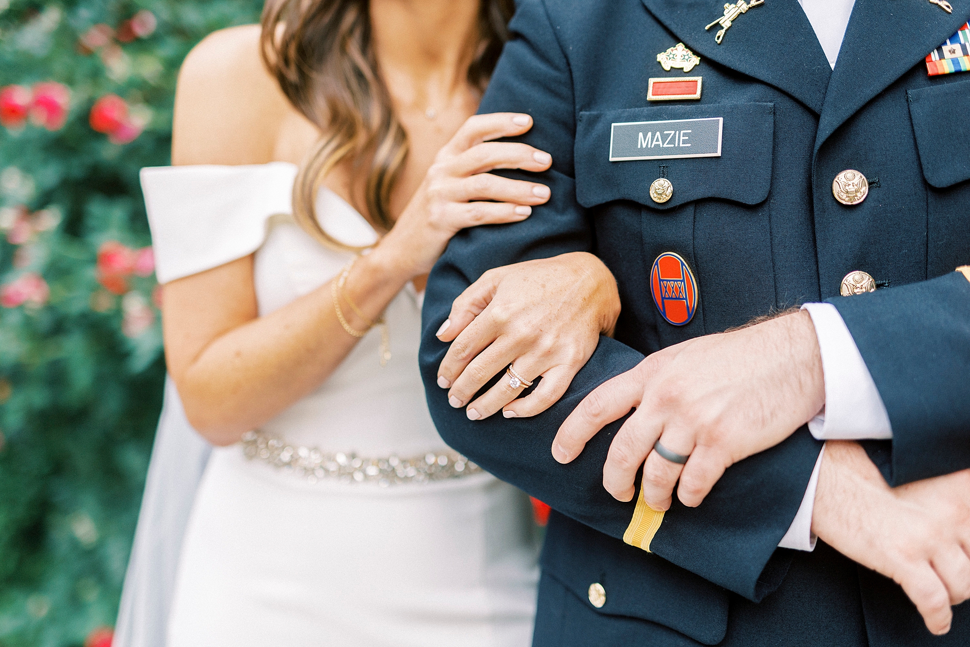 bride holds groom's arm in military dress blues showing off engagement ring