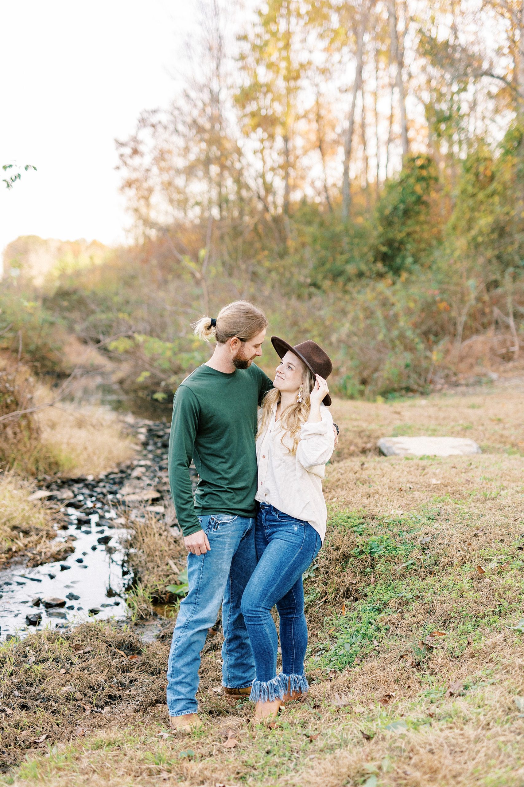 engaged couple hugs smiling together by creek near home in Richfield NC