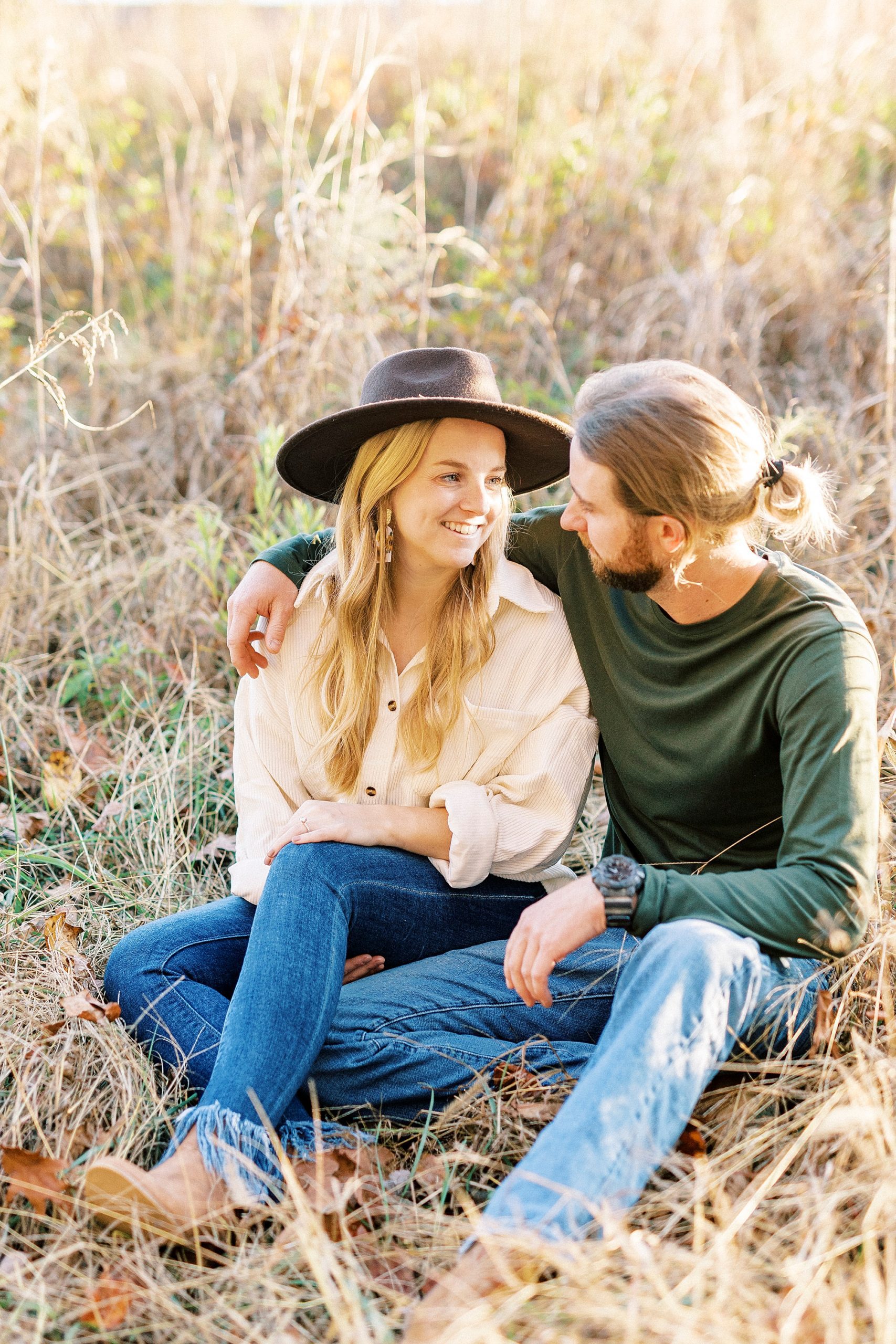 bride and groom sit together hugging during chic fall engagement session