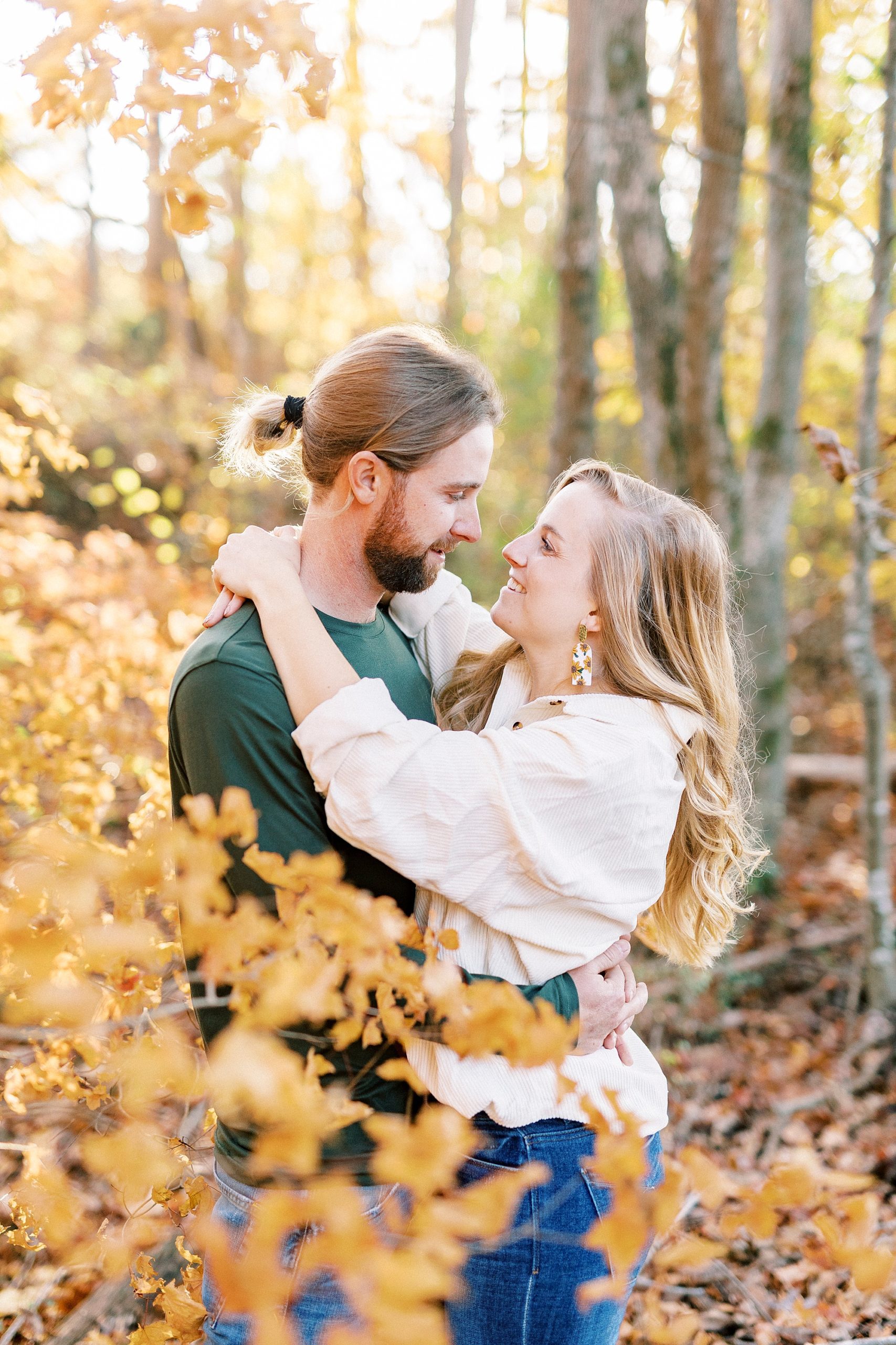 bride and groom hug by yellow leaves during chic fall engagement session