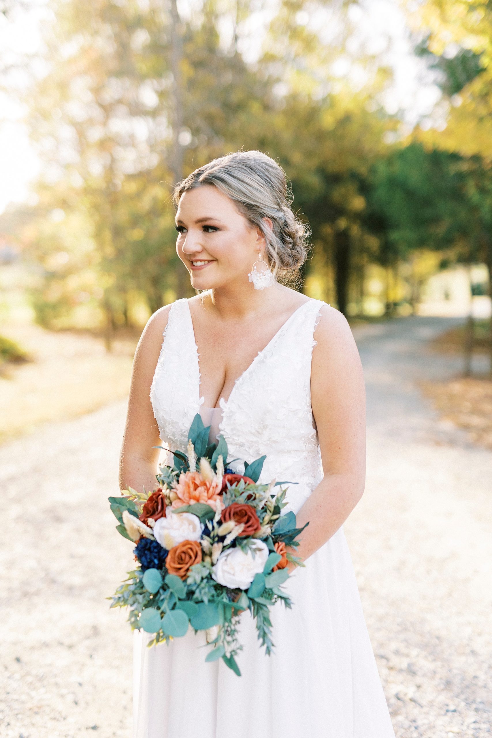 bride smiles looking over shoulder holding fall bouquet 