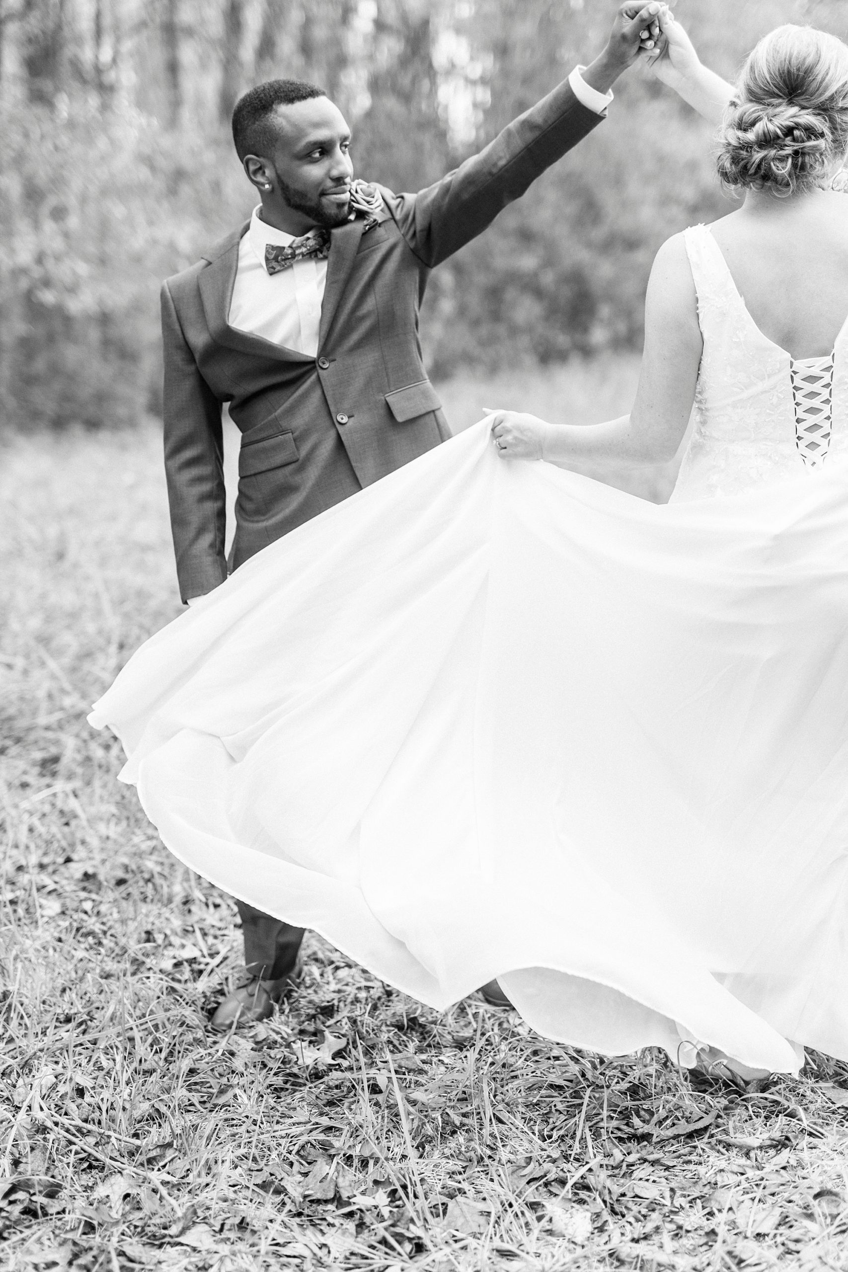 bride holds out skirt while groom twirls her under his arm 