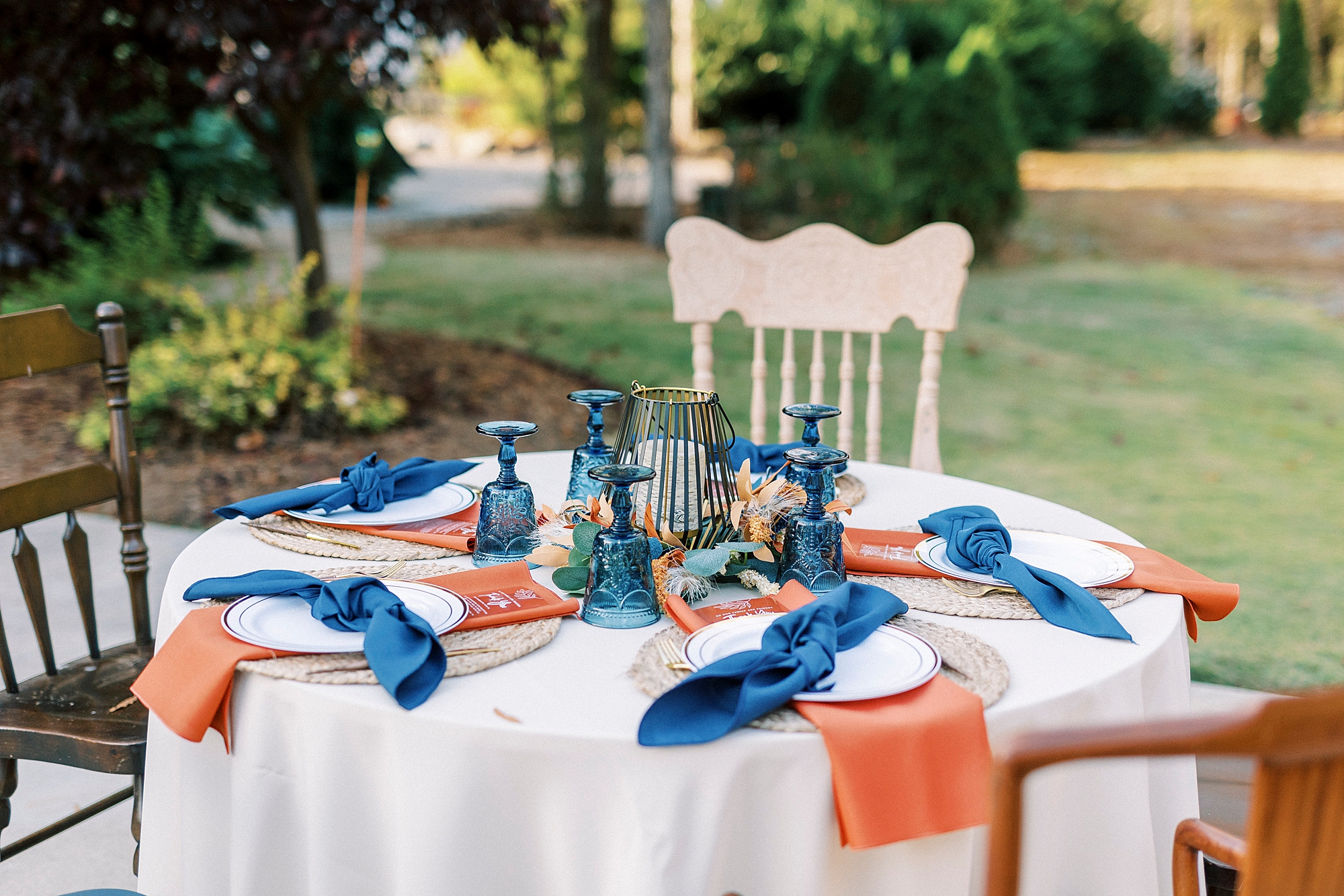 outdoor wedding reception place setting with navy napkins and burnt orange details 