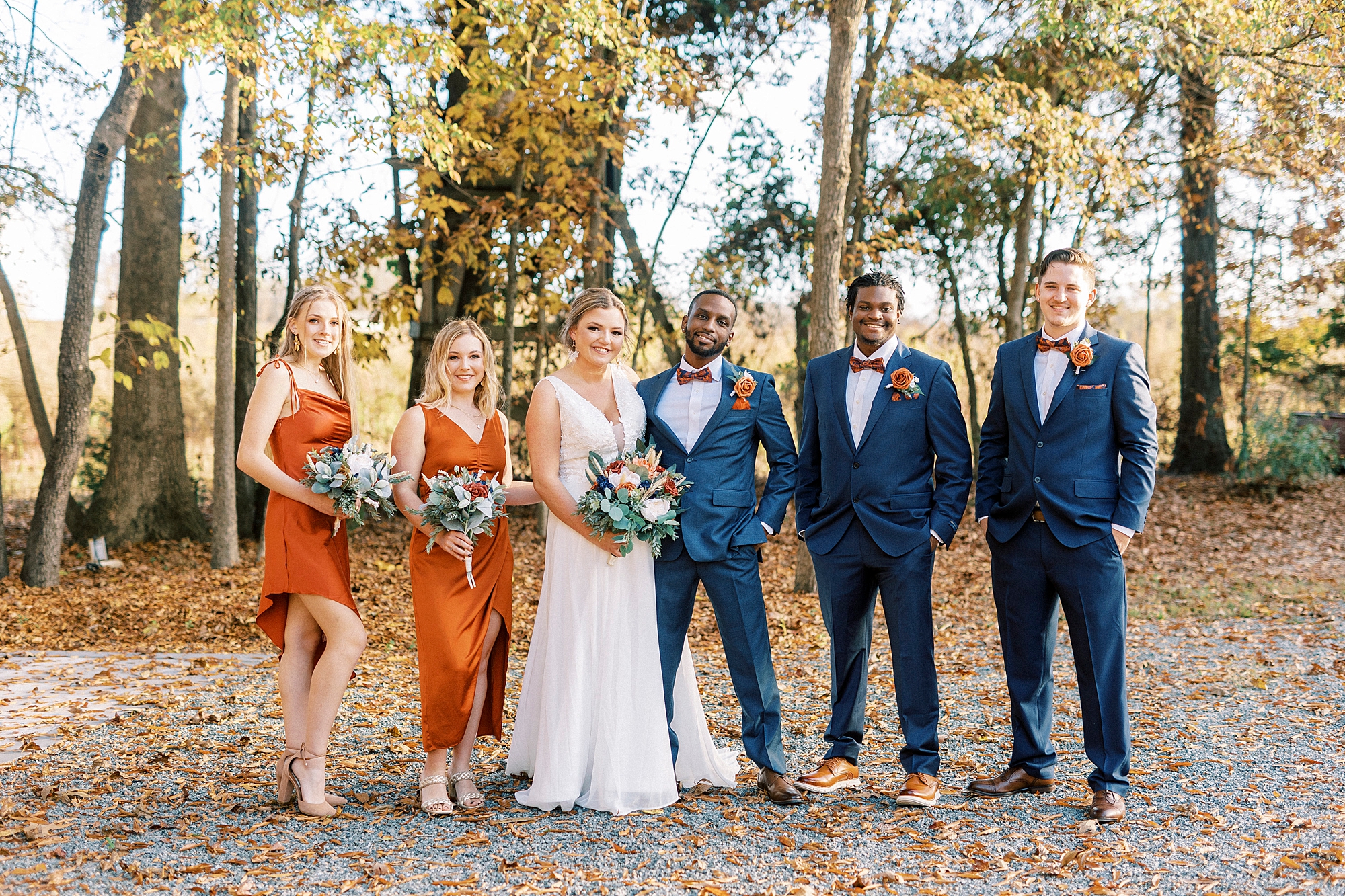 bride and groom pose with wedding party in leaves at Bella Terra 
