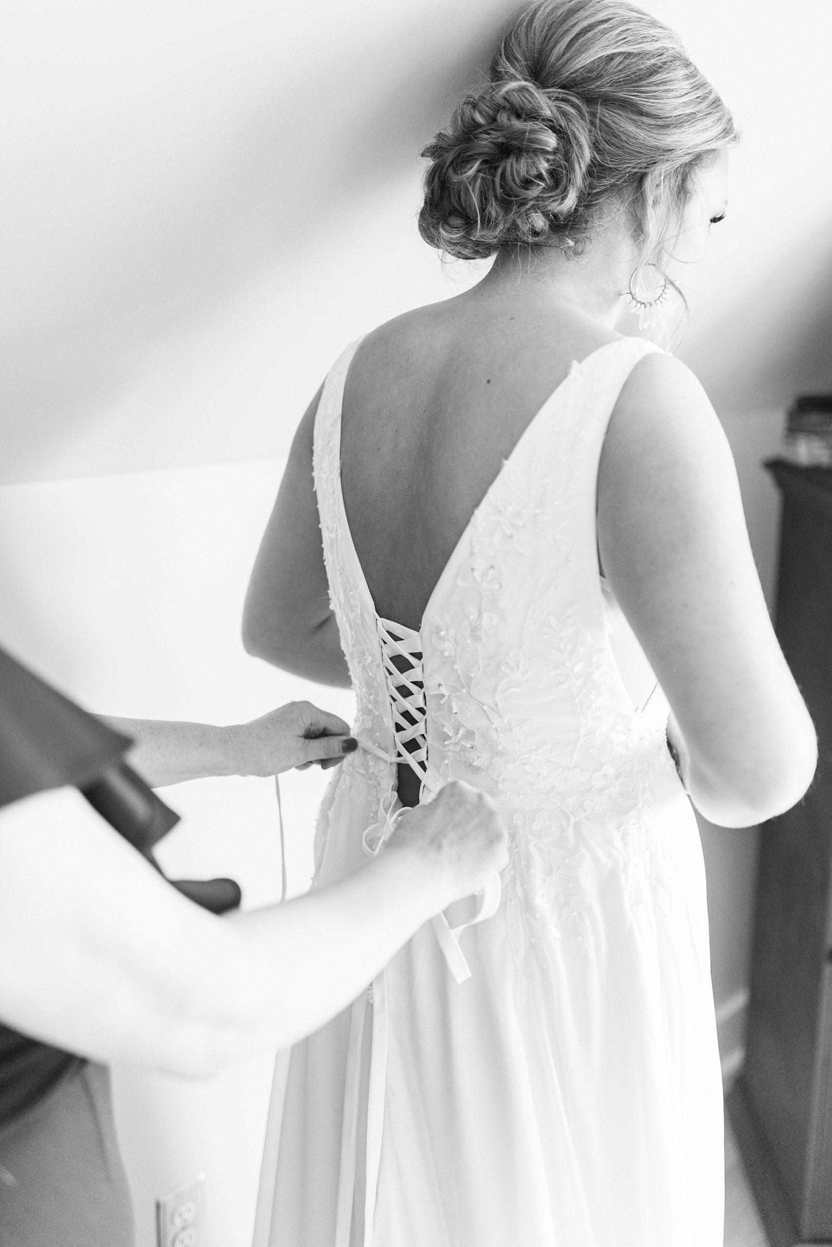 mother laces up back of wedding gown 